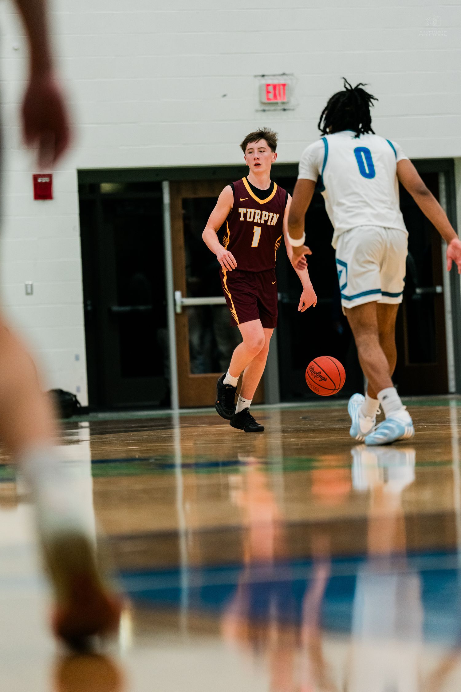 Turpin #1 brings ball upcourt against Warriors #0 defender during high school basketball game.