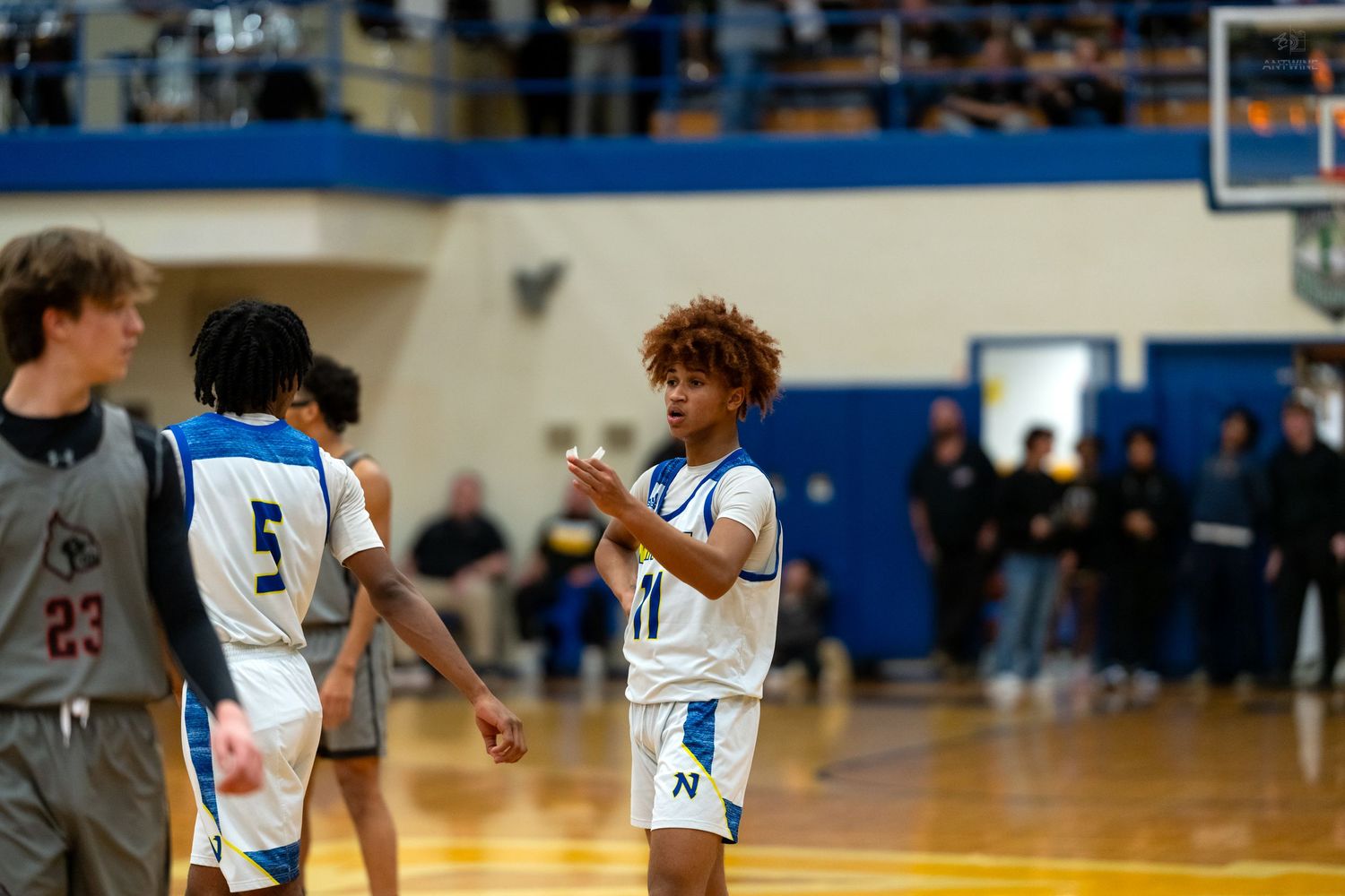 High school basketball player number 11 in blue and white uniform claps hands during game timeout.