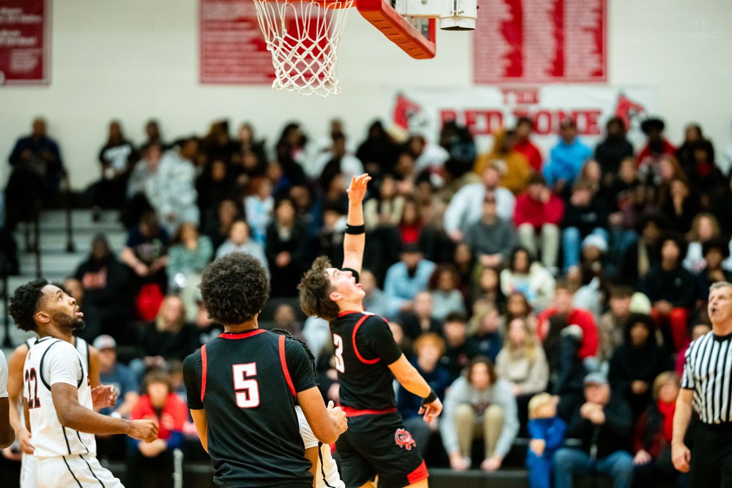 Colerain Cardinals player #5 attempts layup as teammate watches during packed high school basketball game.