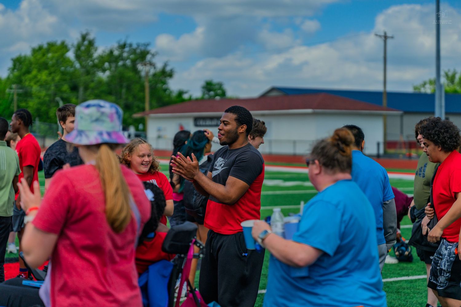 Diverse group of people socializing on a sports field during an outdoor community gathering event.