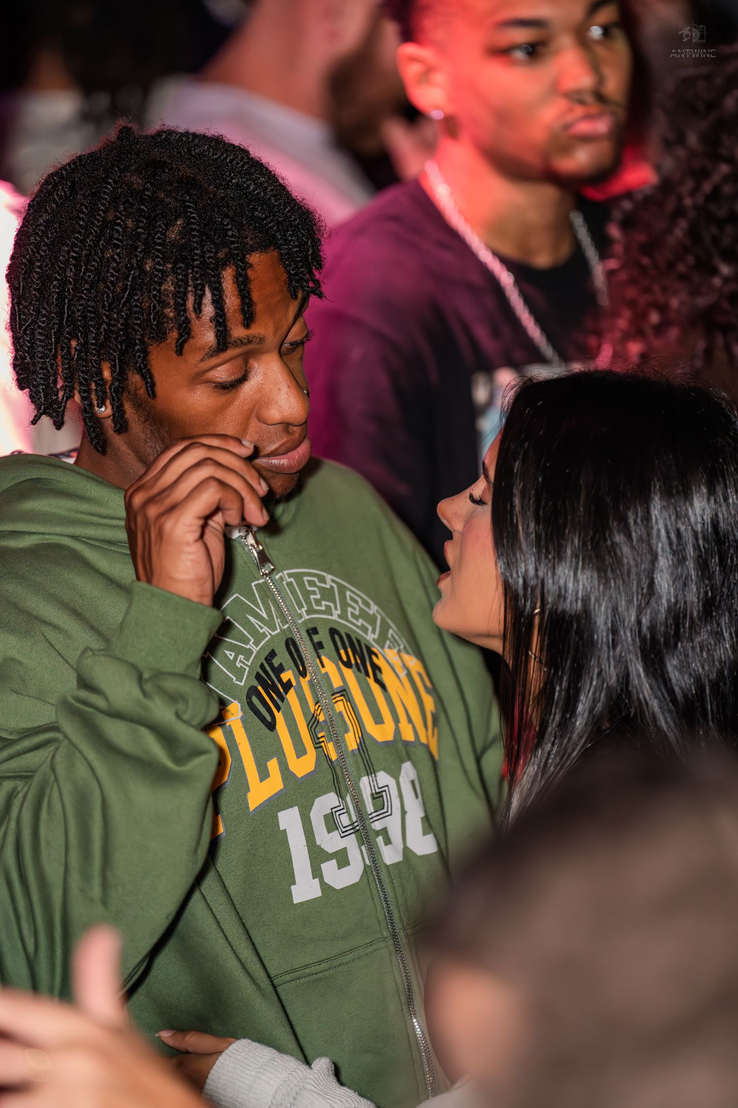 Man in green Morehouse 1956 hoodie sharing an intimate moment with a woman at a nightclub.
