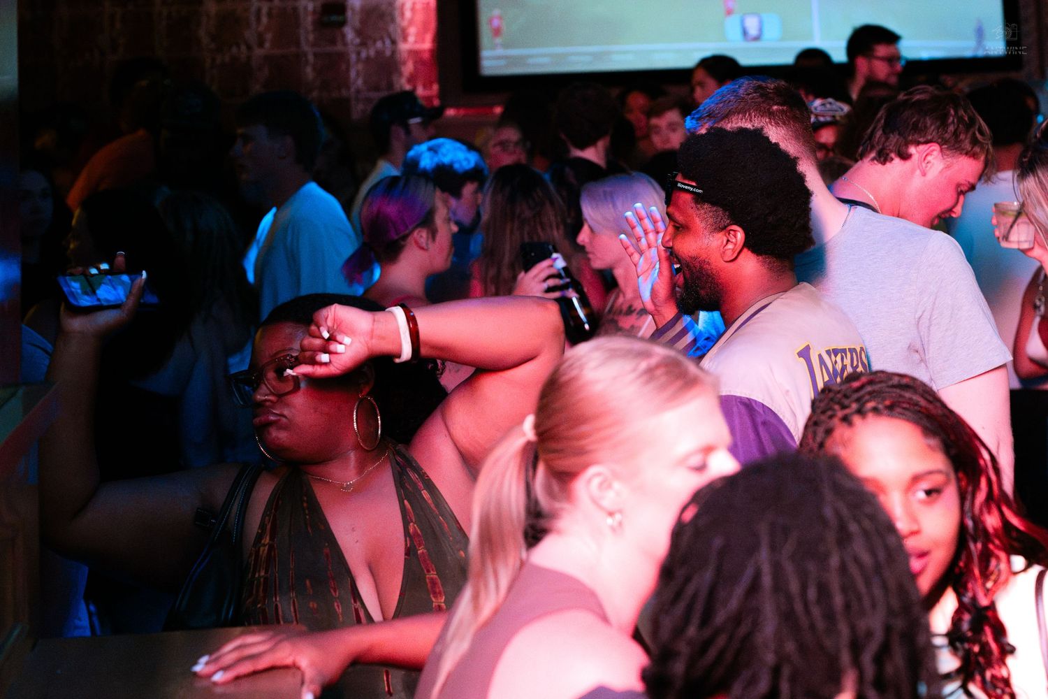 Diverse crowd of people dancing and socializing at a packed nightclub party.