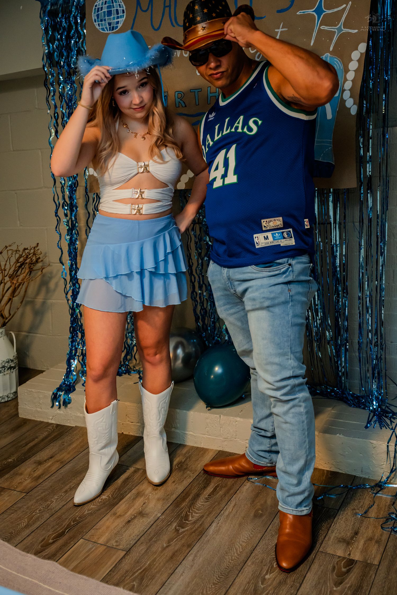 Two friends adjust their hats while posing at Malarie's blue-themed 21st birthday party.