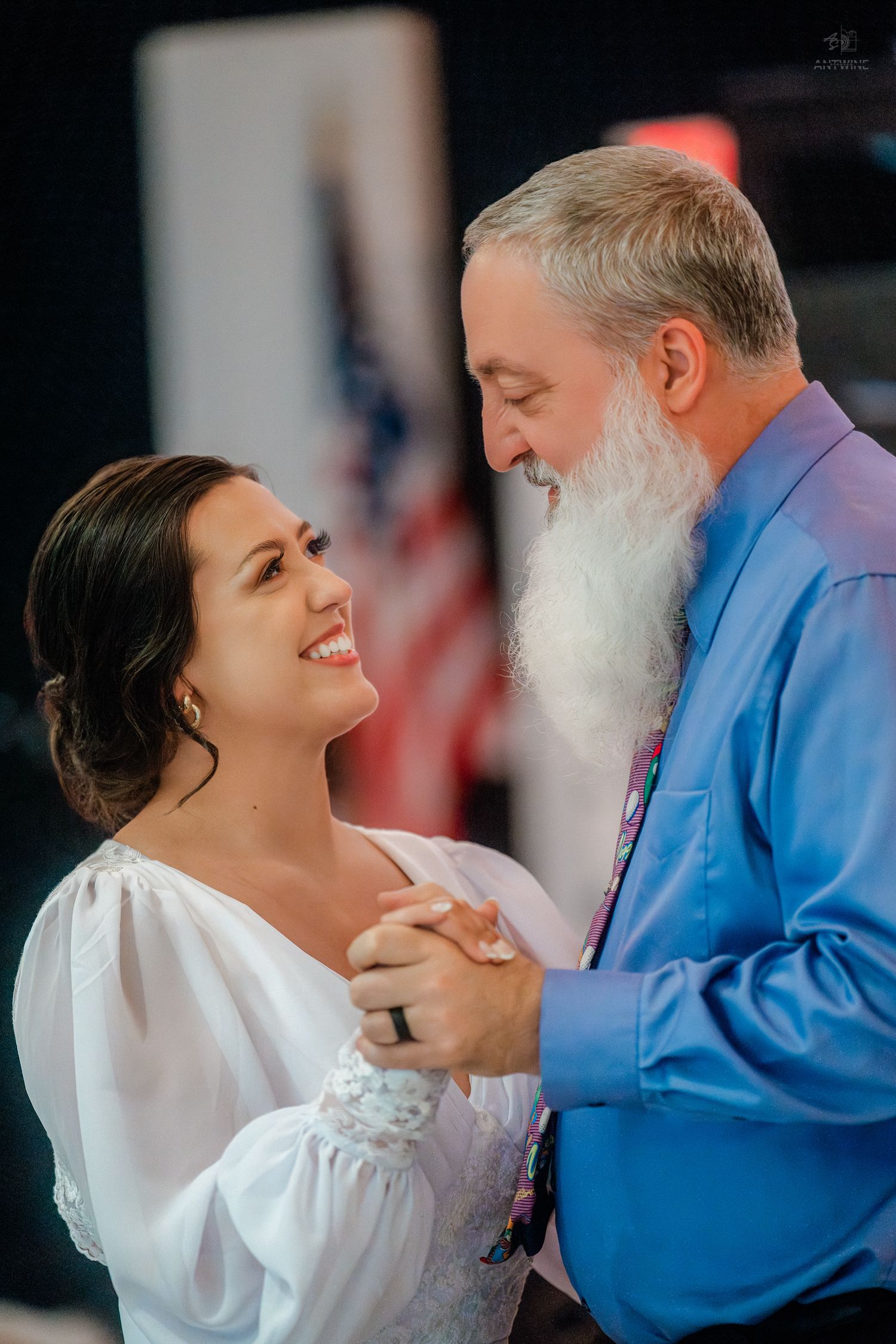 Bride and older man with white beard share a father-daughter dance at wedding reception.