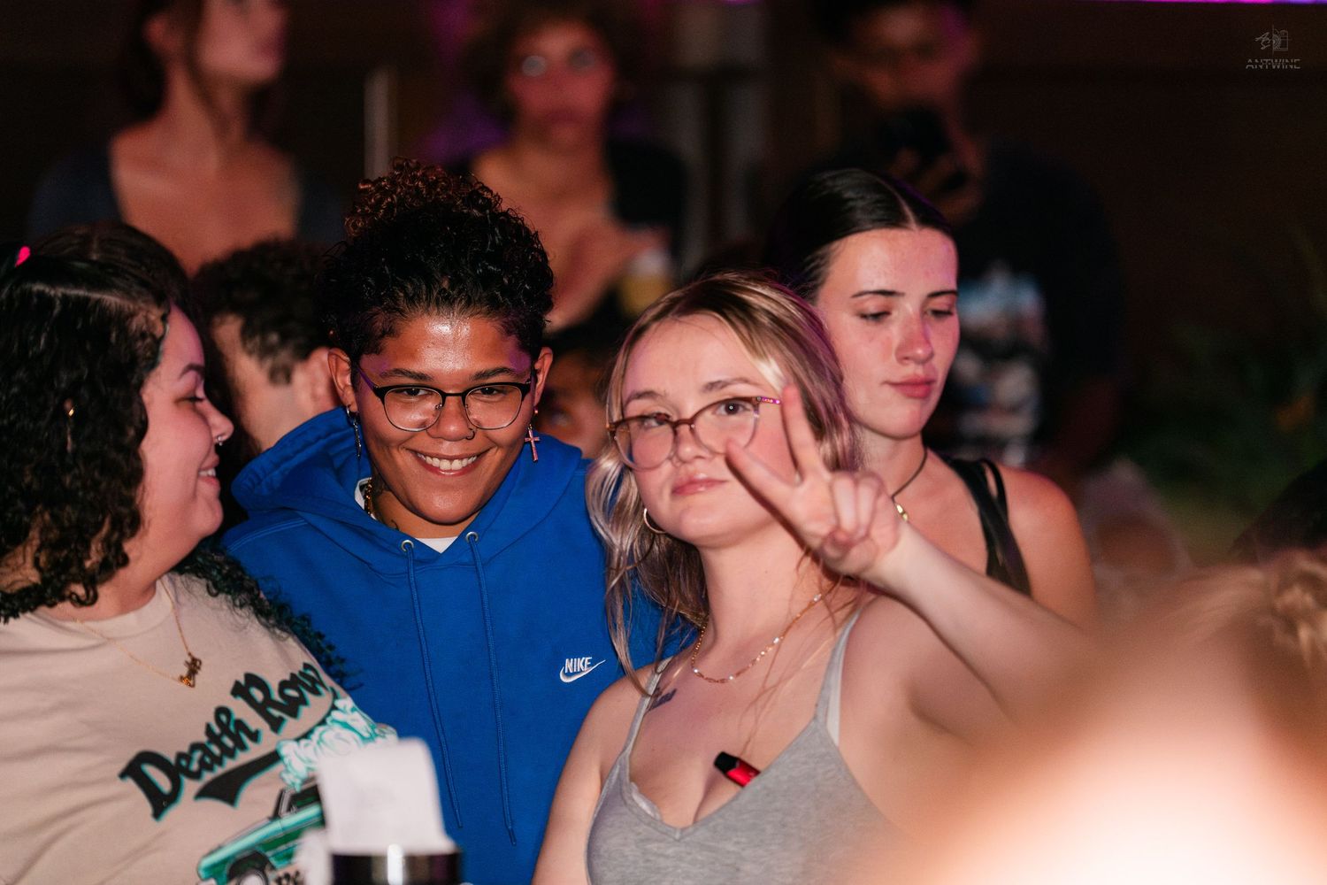 Group of young friends smiling and posing together at a lively indoor party or nightclub event.