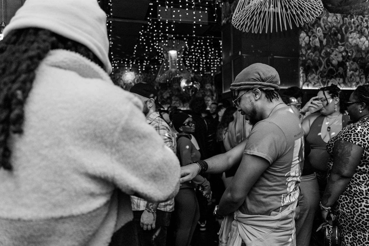 Black and white photo of people dancing and socializing at an outdoor nighttime party event.
