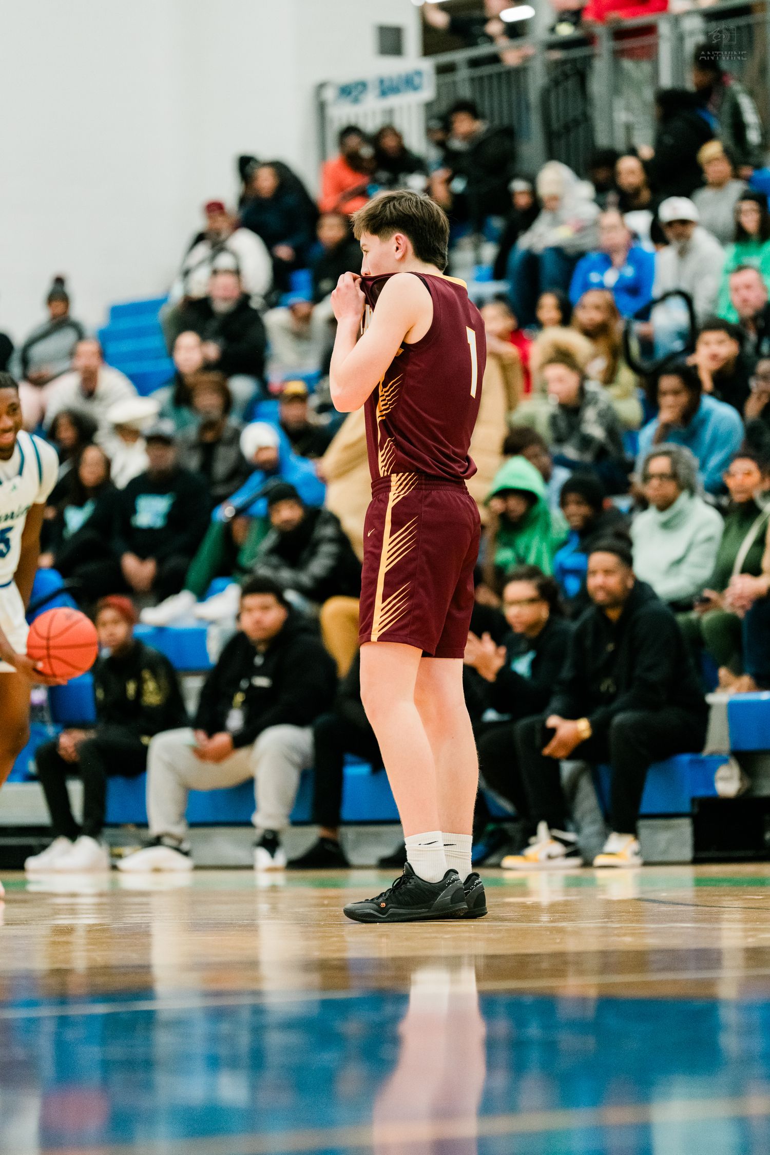 A basketball player in a maroon uniform clasps hands near face while a Warriors defender approaches on court.