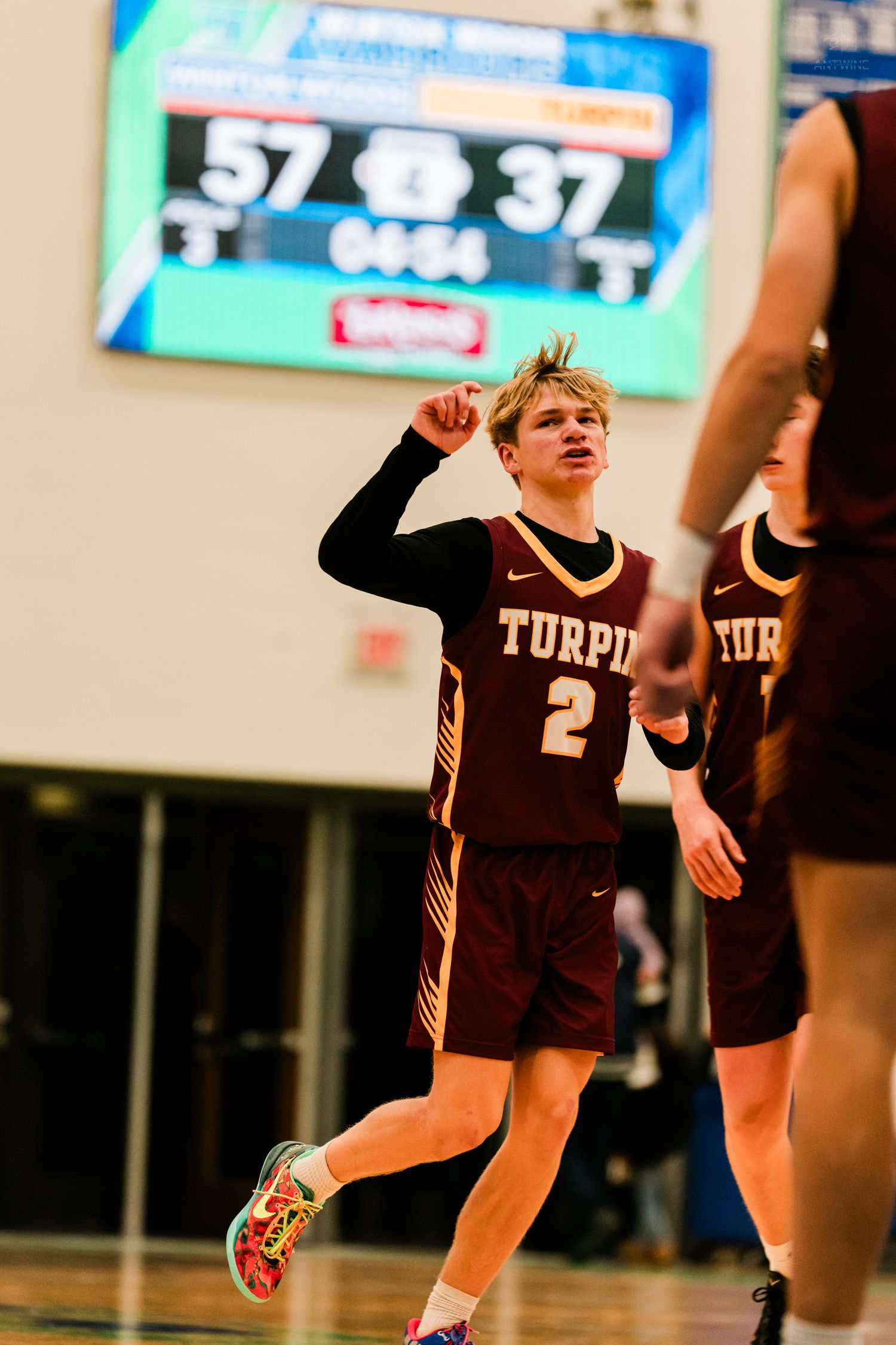 Turpin player #2 celebrates while scoreboard shows 57-37 during a high school basketball game.