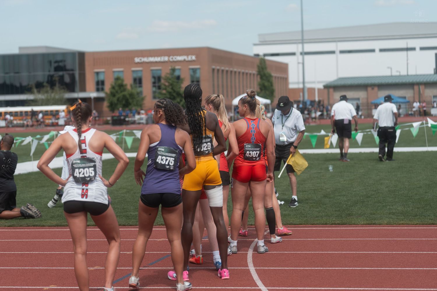 Group of female track athletes wait near the starting area at a high school state championship track meet.