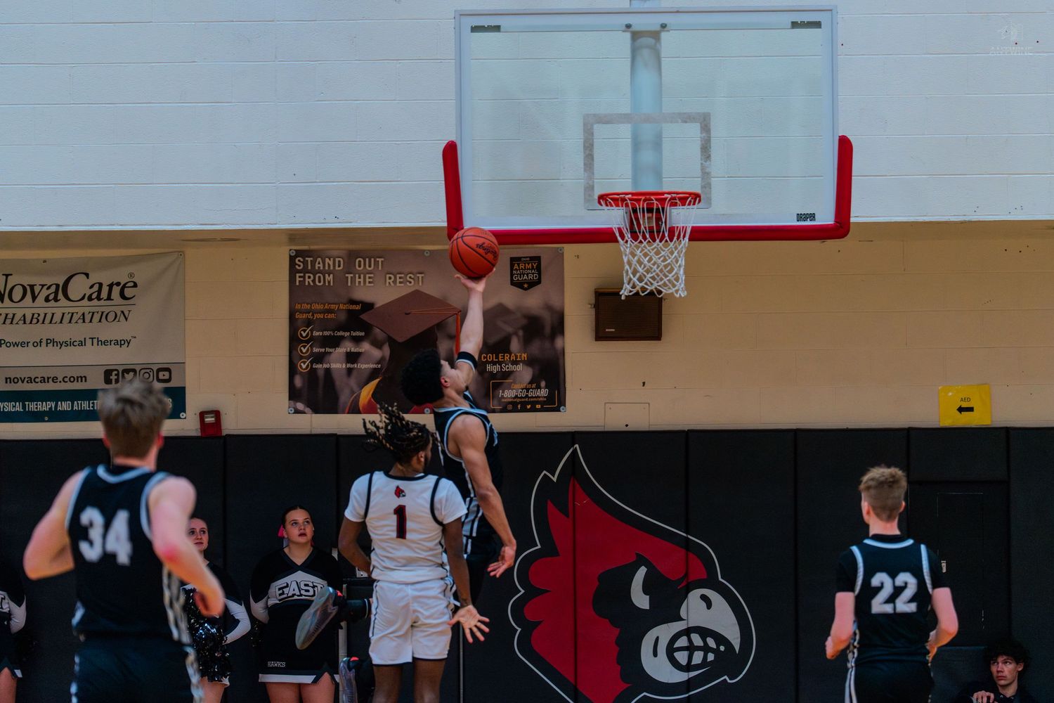 High school basketball player shoots layup during competitive gym game.
