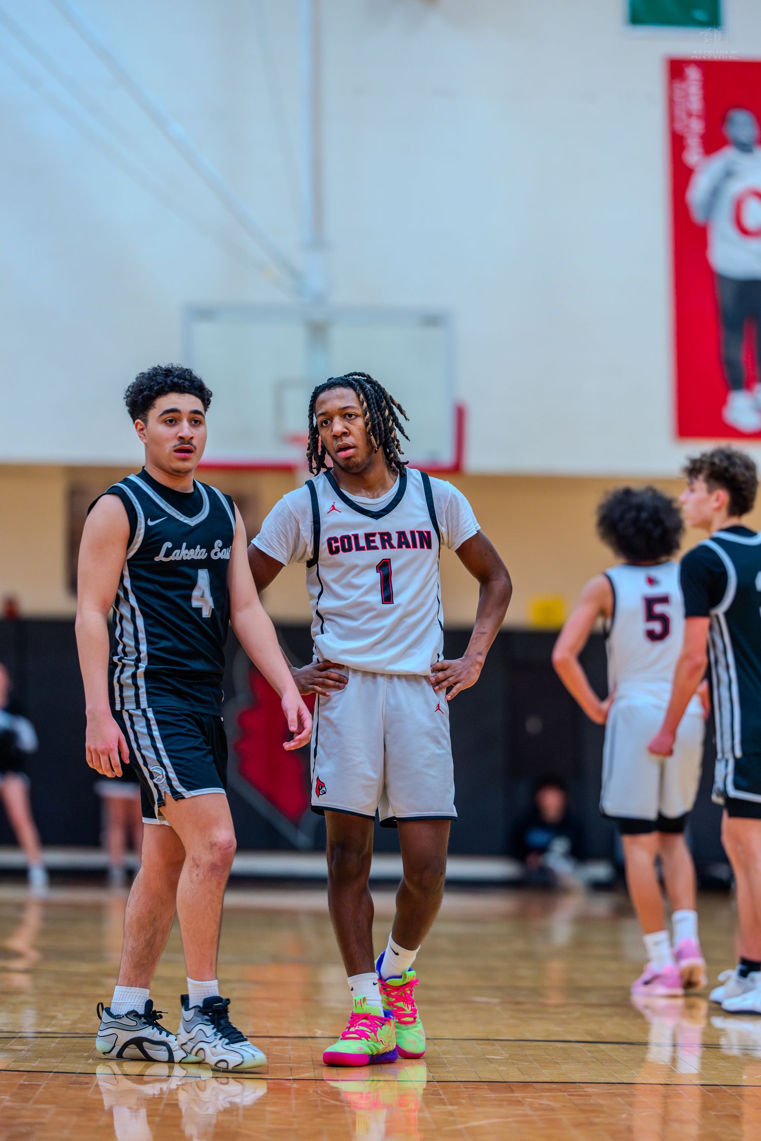 Colerain #1 stands beside a Lake Erie opponent #4 during a high school basketball game.