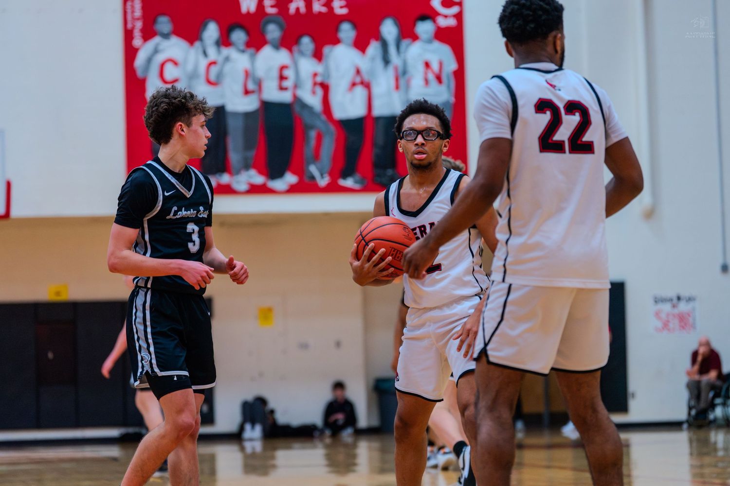 A Colerain basketball player in white uniform holds the ball while being guarded during a home game.