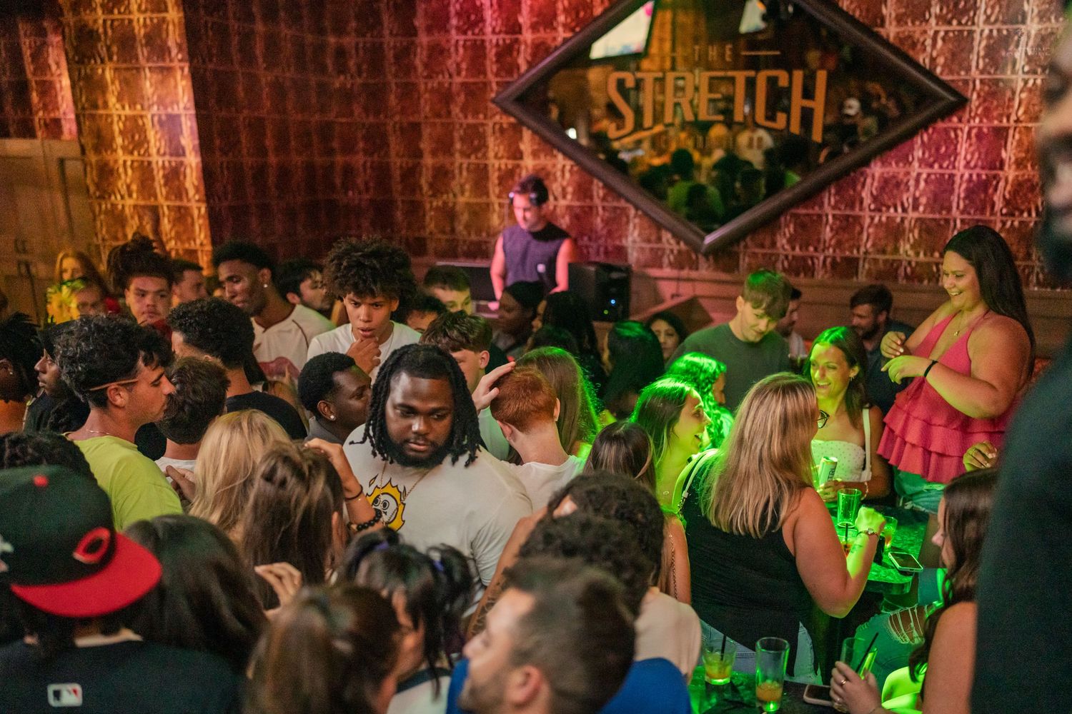 Crowded nightclub dance floor with green lights under a Stretch bar sign.