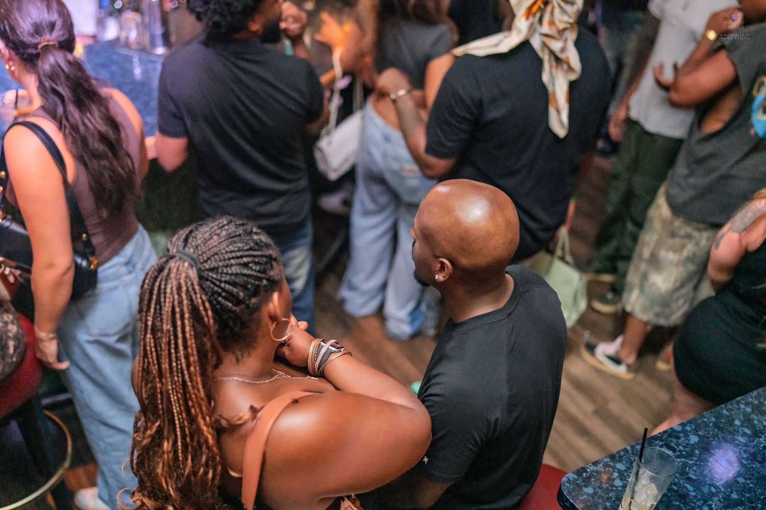 Couple embracing and socializing together in a packed nightclub with soft ambient lighting.