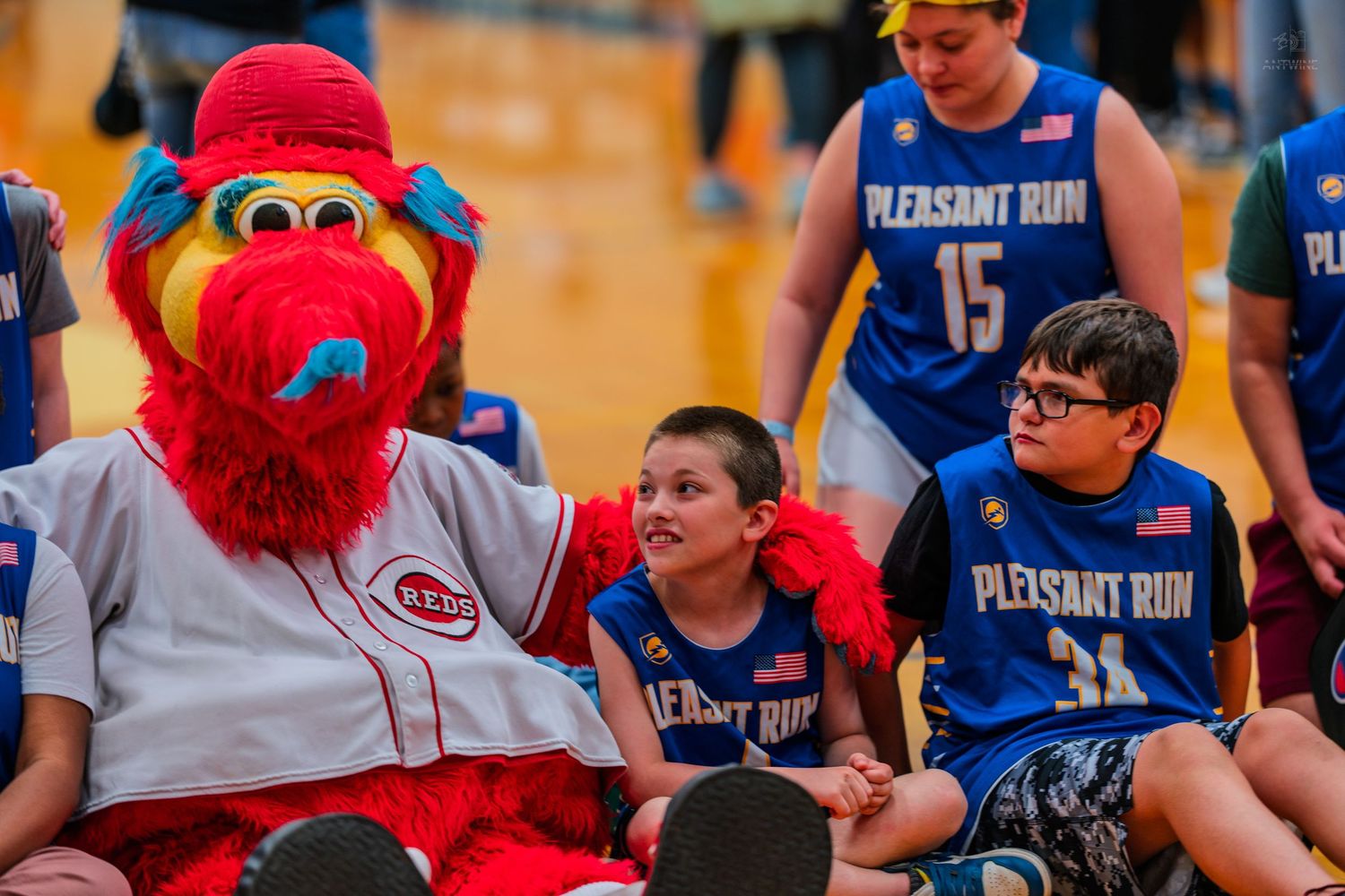 Cincinnati Reds mascot Mr. Redlegs poses with young Pleasant Run basketball players during a school sports event.