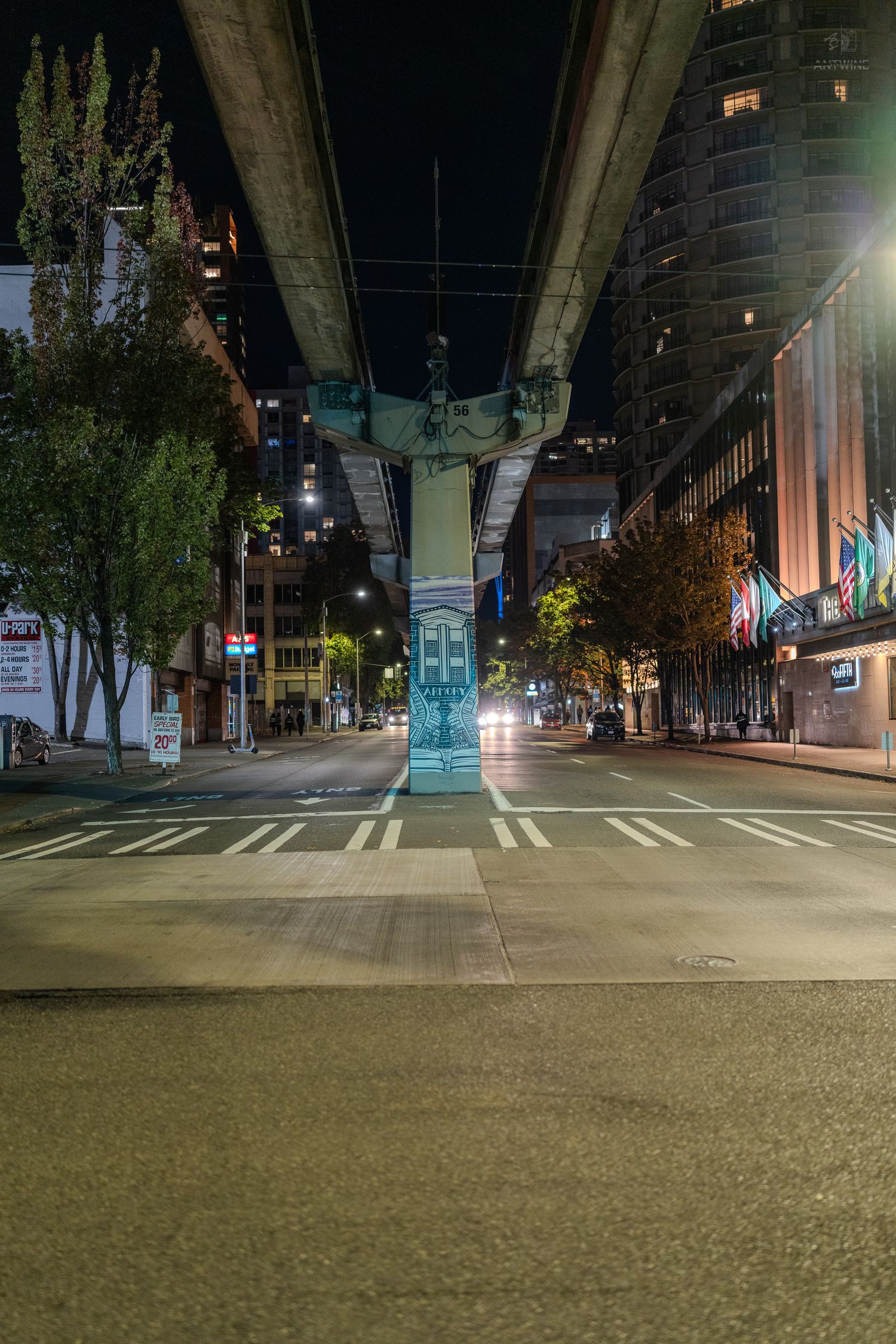 Night urban street scene under an elevated highway overpass with city lights and buildings in Seattle.