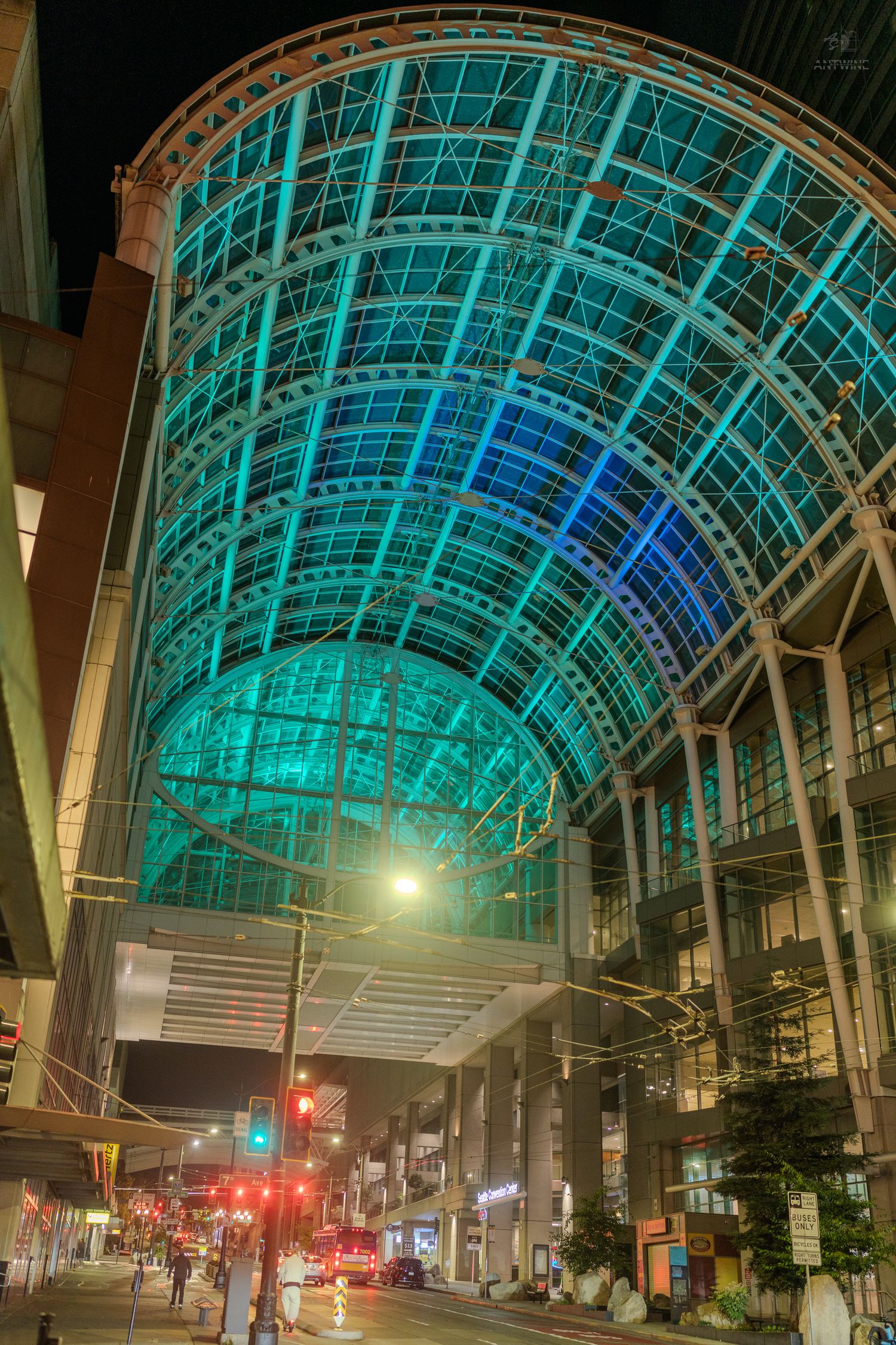 Seattle Convention Center glowing arch roof illuminated in teal and blue lights at night.