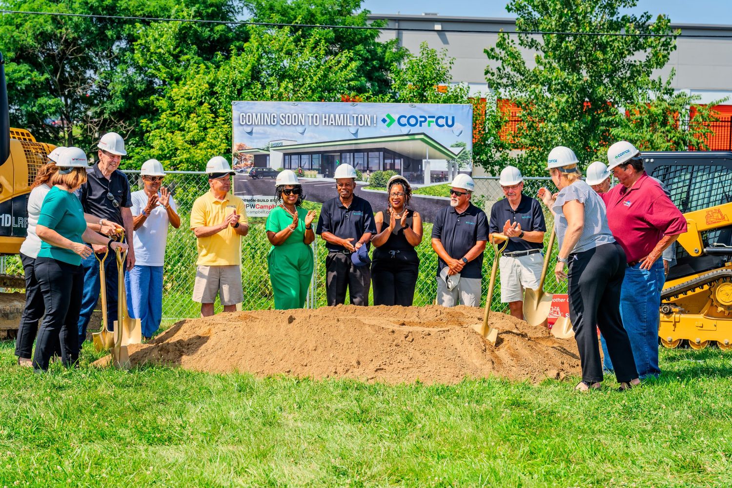Large group clapping and celebrating at COPFCU groundbreaking ceremony outdoors.