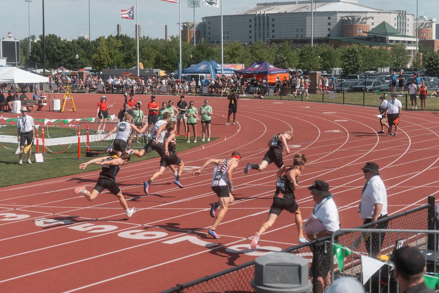 High school track athletes sprint toward the finish line during an outdoor relay race competition.