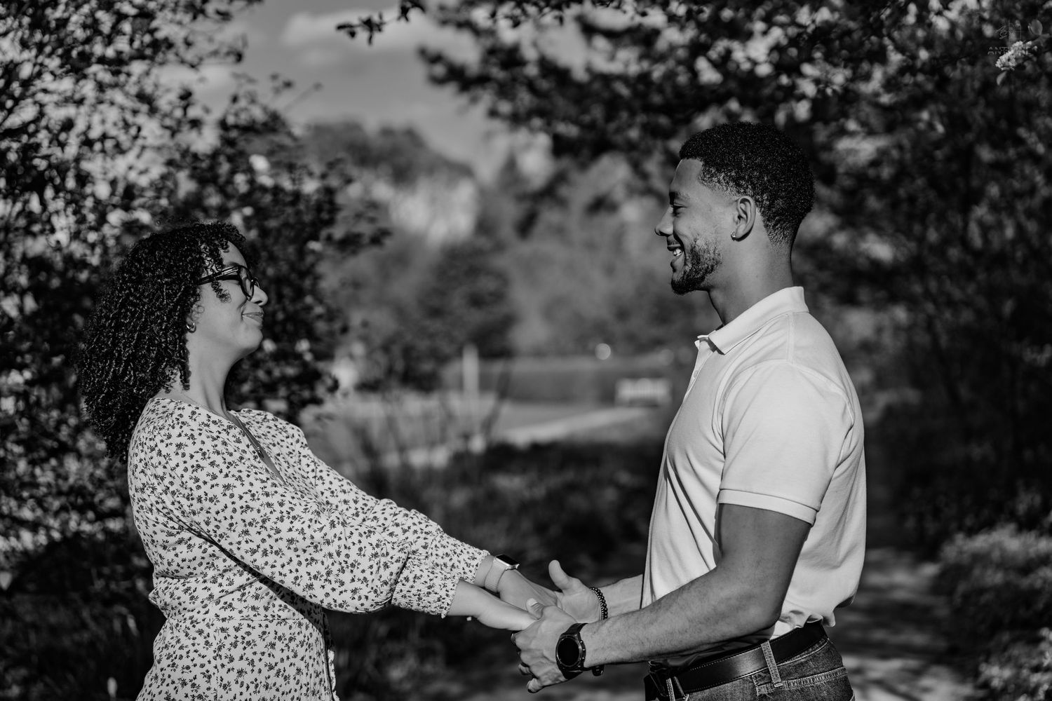 Black couple holding hands and gazing at each other in a black and white outdoor portrait.