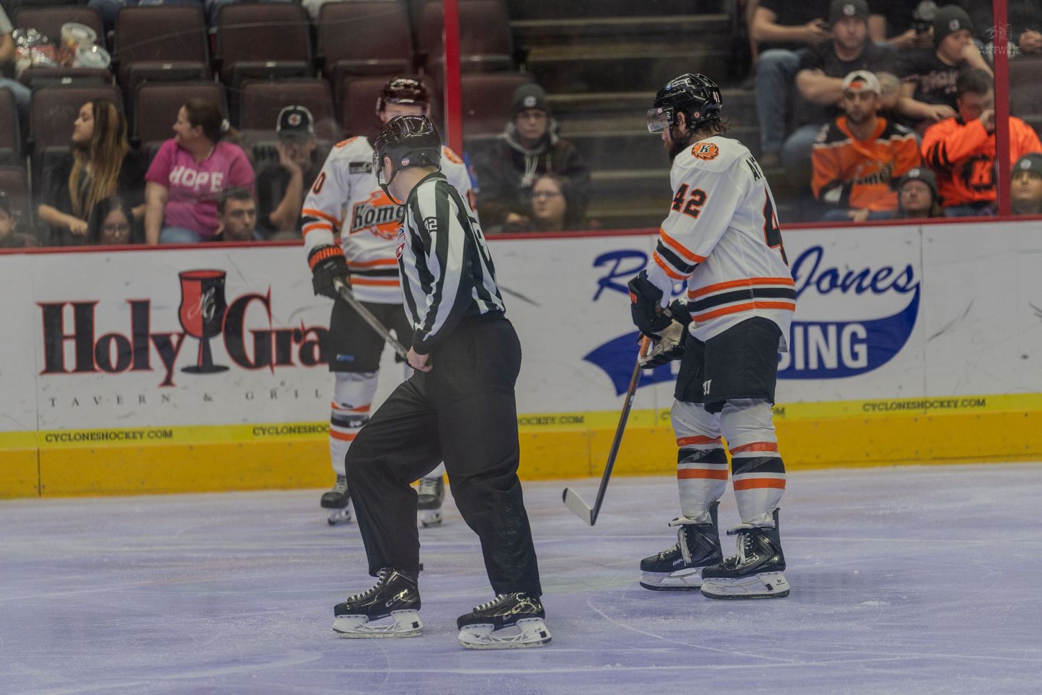 Hockey referee stands near player number 42 during a stoppage in play.