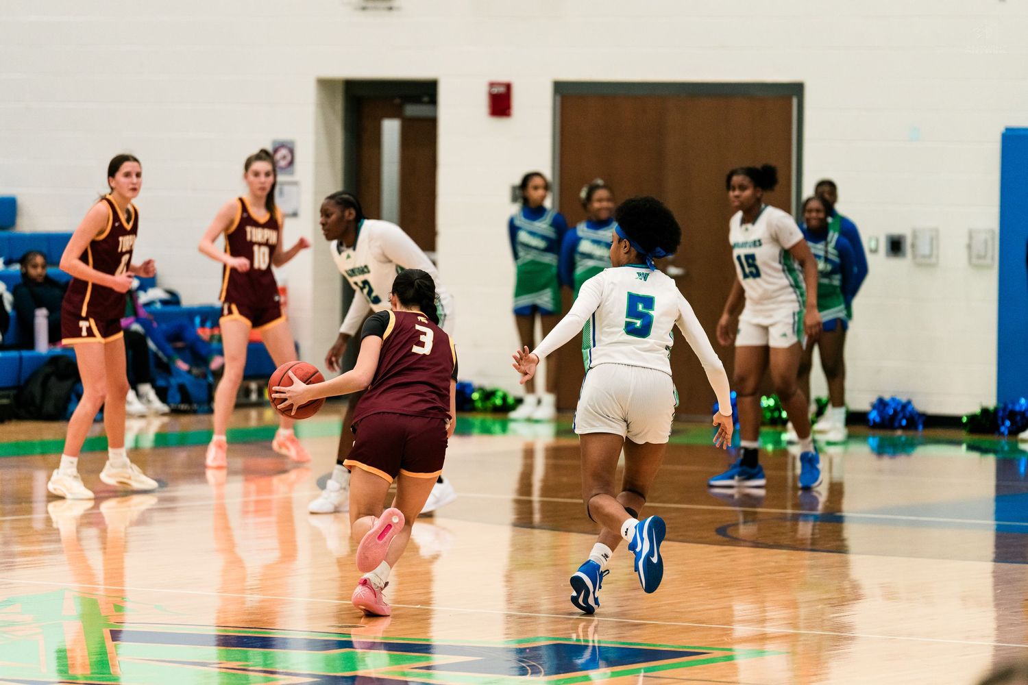 Turpin girls basketball player dribbles as Warriors defenders close in during high school game.