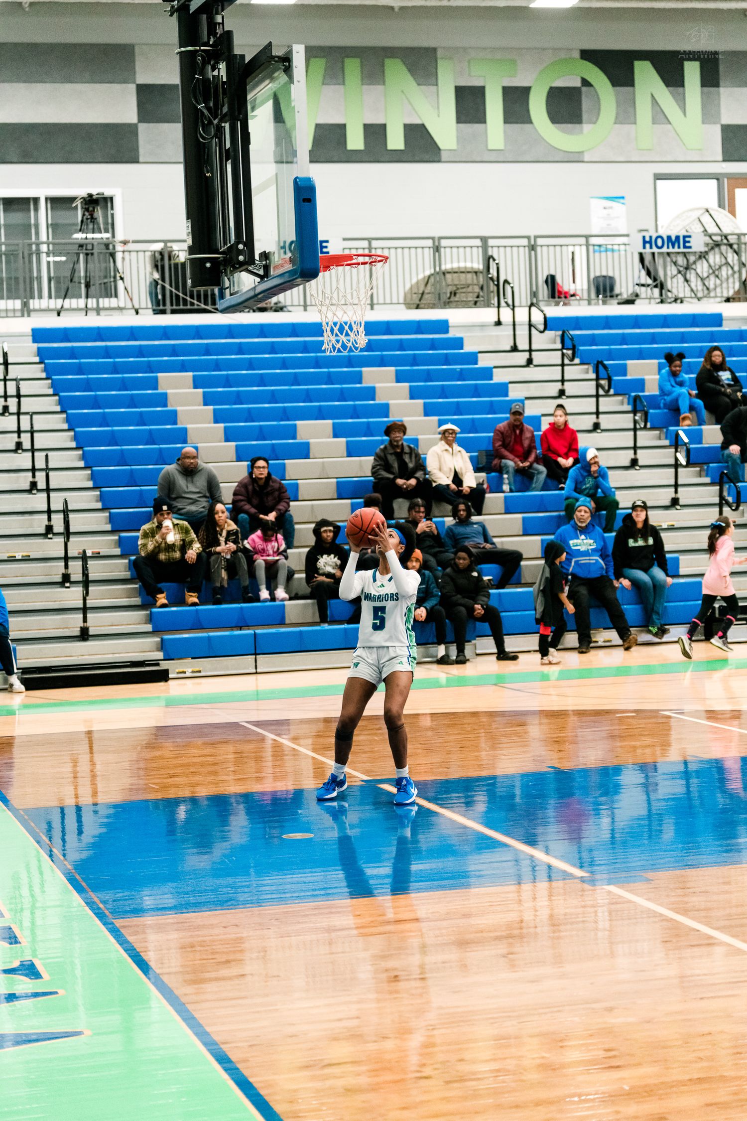 A girls basketball player in white shoots a free throw in an empty Vinton gymnasium during a high school game.