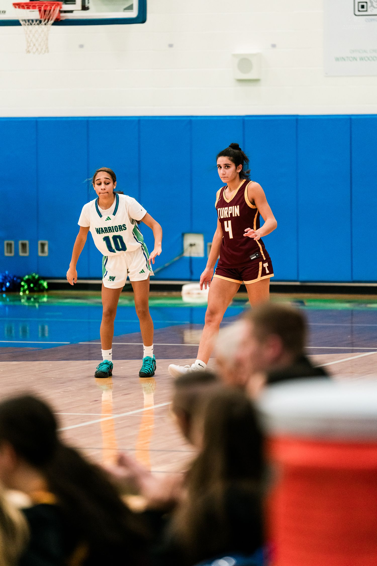 Warriors number 10 guards a Turpin number 4 player near the baseline during a girls high school basketball game.