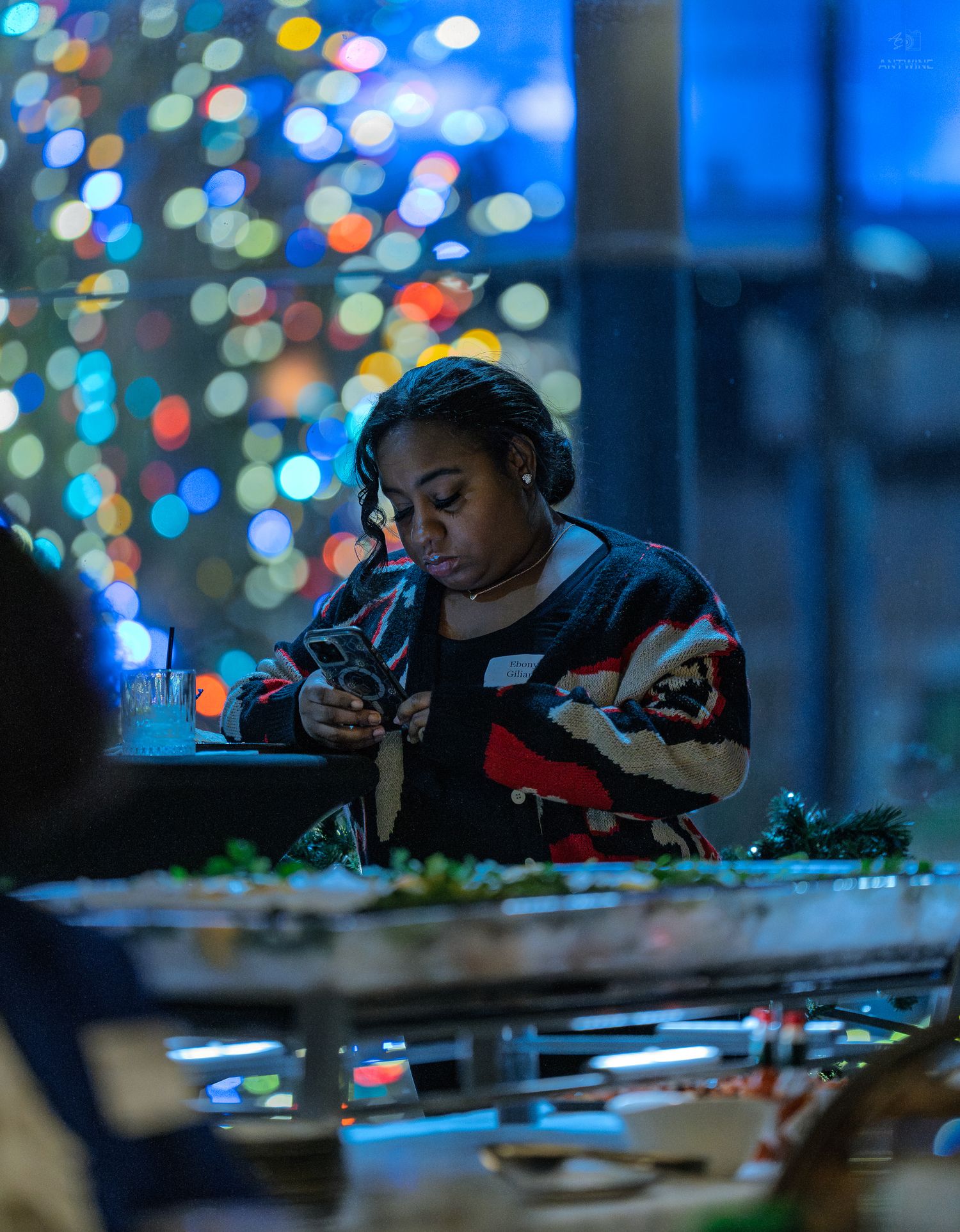 Woman in festive sweater serving food at a holiday buffet with colorful bokeh lights in the background.