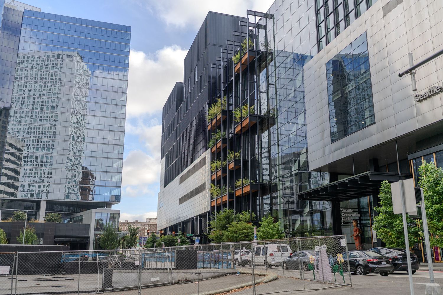 Contemporary urban office building with vertical garden greenery facade surrounded by glass skyscrapers in Seattle.