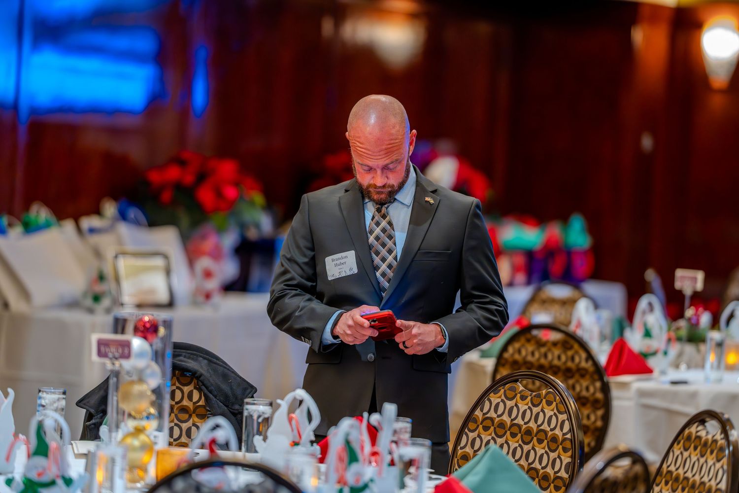 Man in suit examining a card at an elegantly decorated banquet hall with holiday centerpieces.