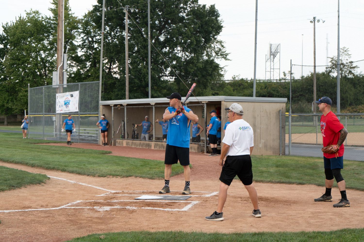 Players enjoy a recreational softball game at a community baseball diamond during a summer evening.