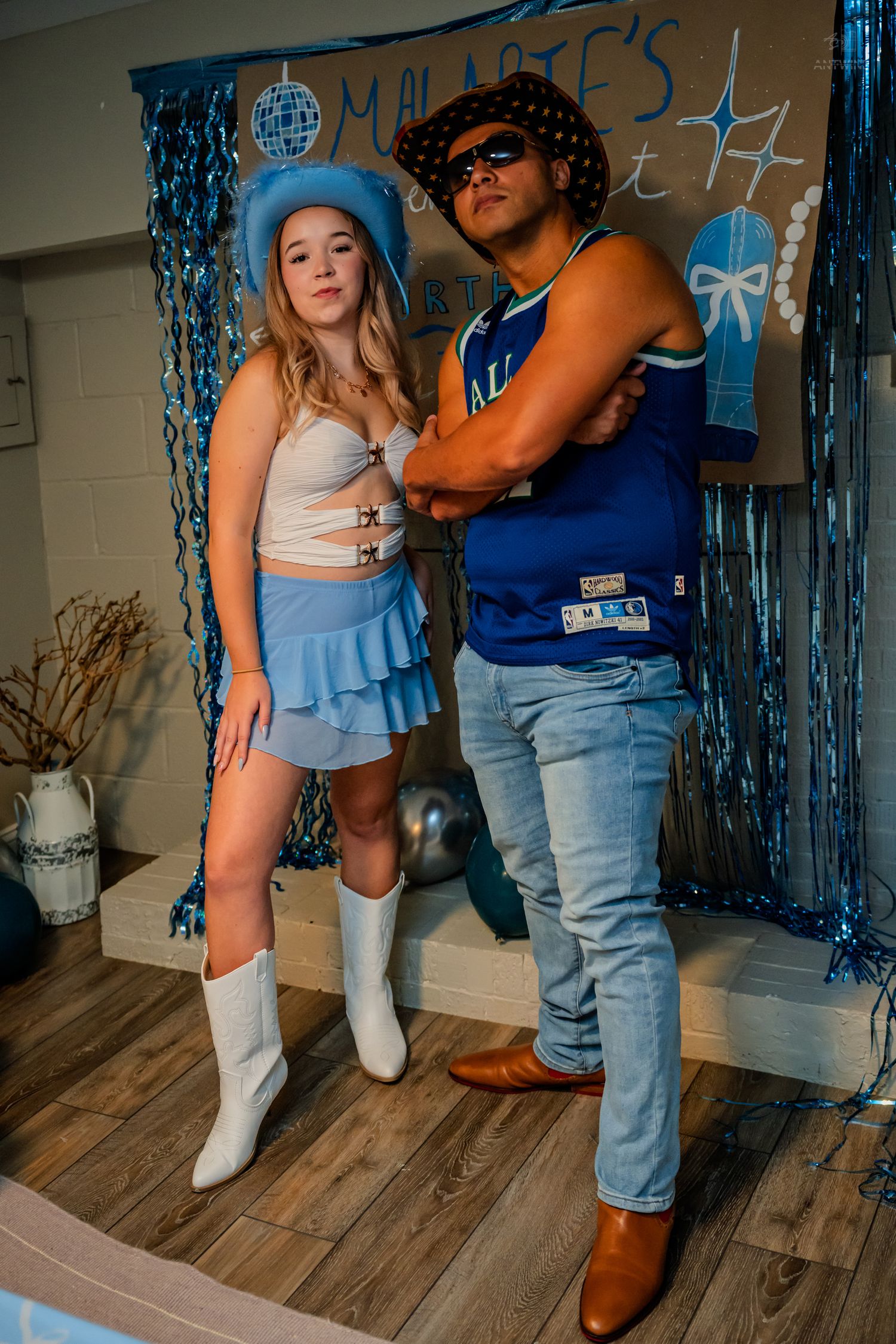 Two party guests strike a serious pose at Malarie's 21st birthday celebration with blue tinsel backdrop.