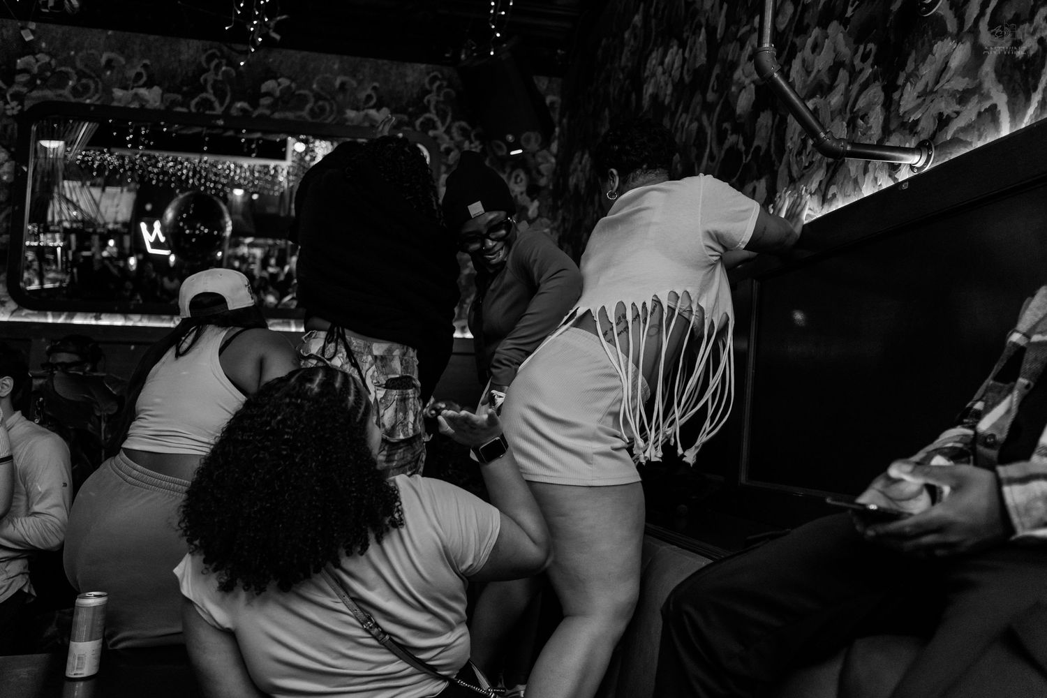 Black and white photo of energetic crowd dancing at a nightclub with decorative lighting.