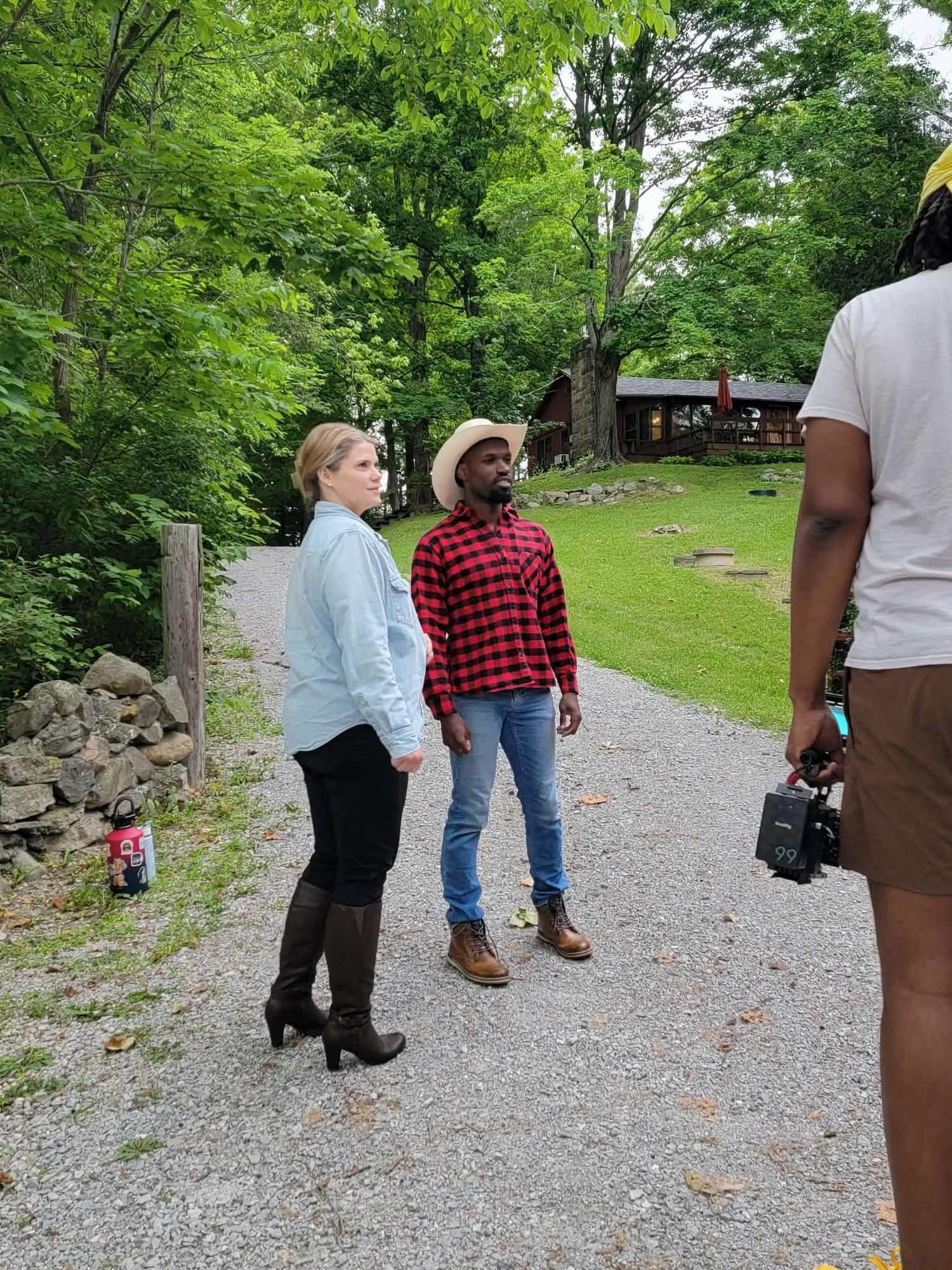Two actors standing on gravel path during outdoor film production shoot.