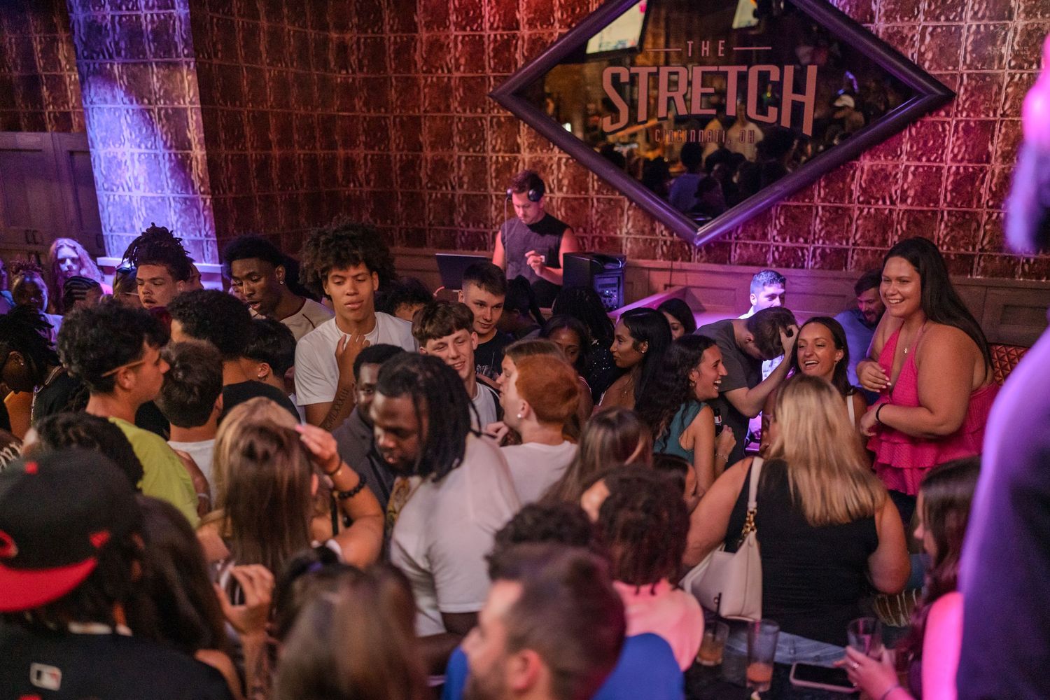 Lively nightclub crowd gathered under the Stretch bar diamond logo sign.