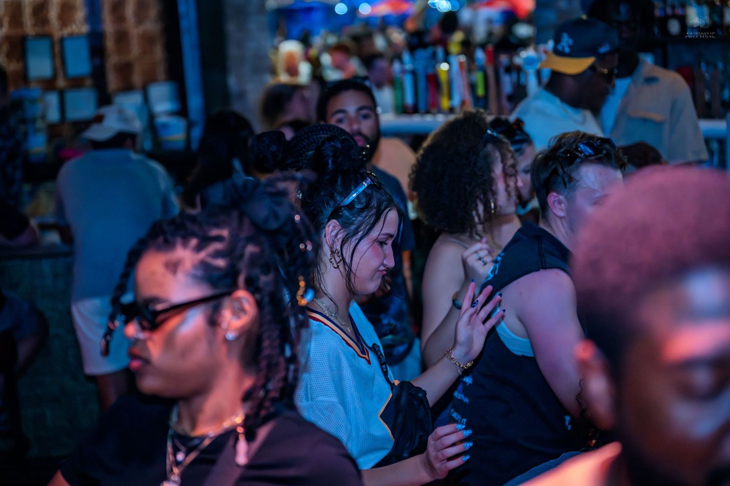 Young couple embracing in a crowded nightclub with moody blue lighting and lively atmosphere.