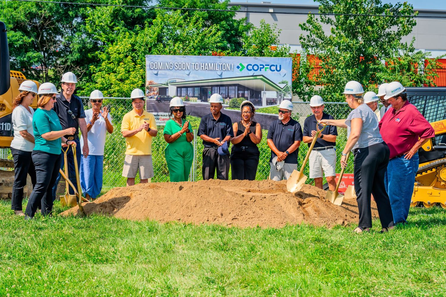 Officials and community members in hard hats at COPFCU Hamilton branch groundbreaking ceremony.
