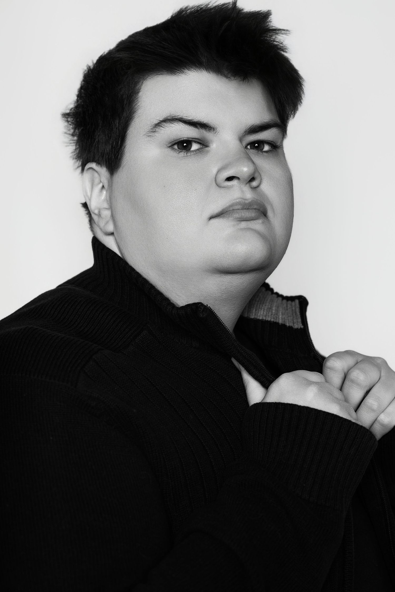Black and white portrait of a young person in a black turtleneck sweater with a serious expression.