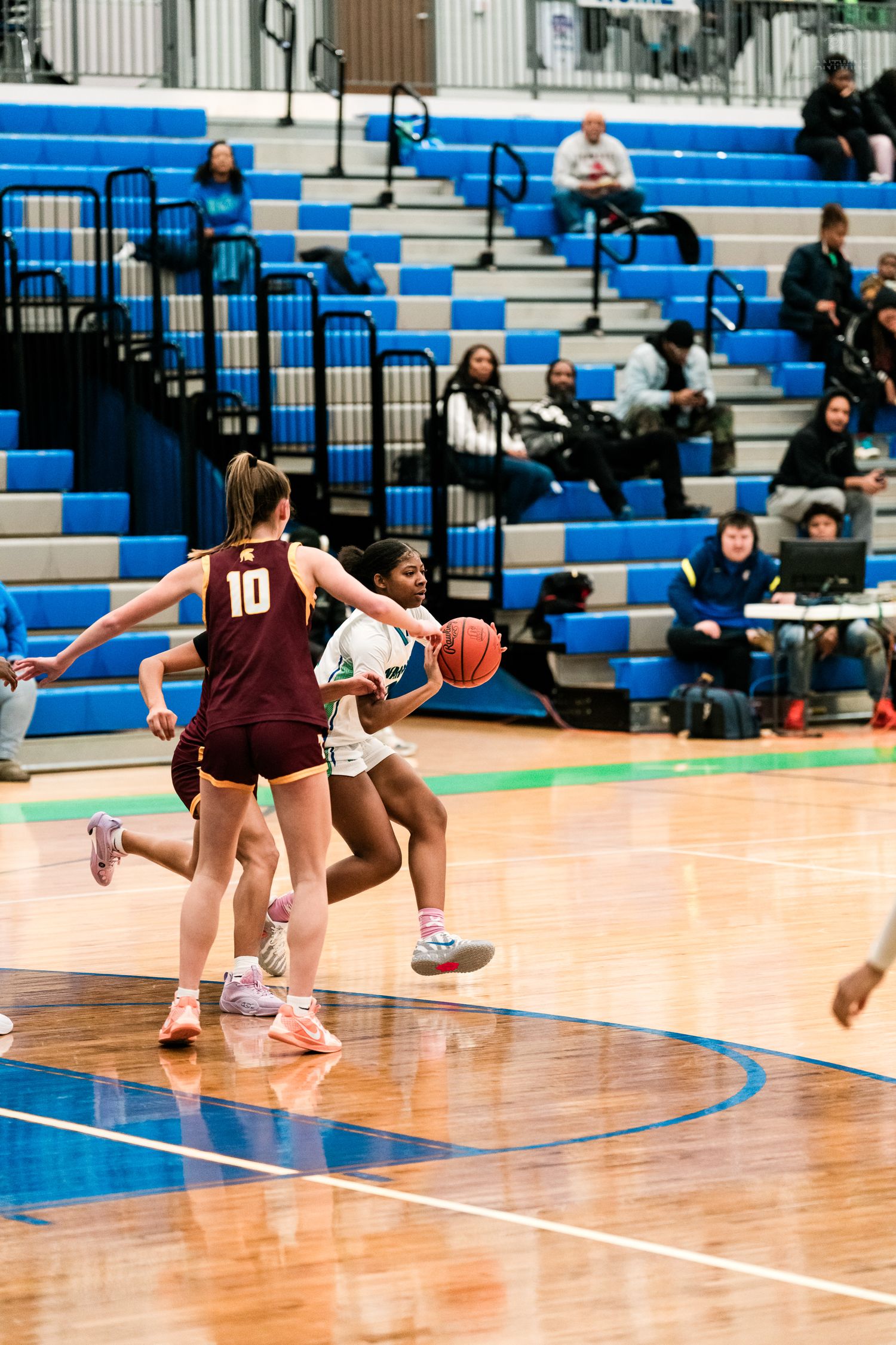 Warriors player drives past Trojan #10 defender toward the basket during girls high school basketball game.