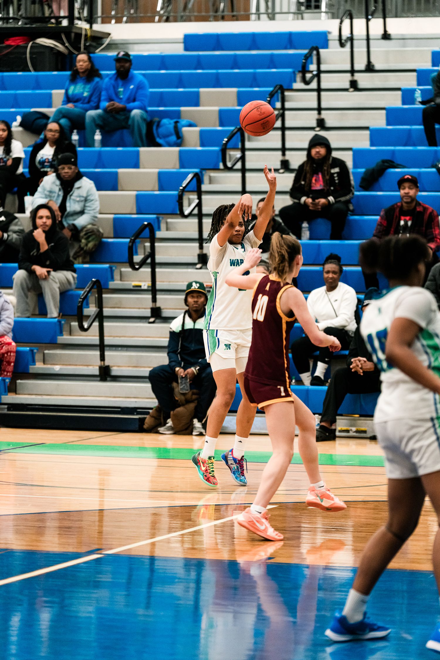 A female Warriors player jumps to shoot over a Turpin defender during a girls high school basketball game.