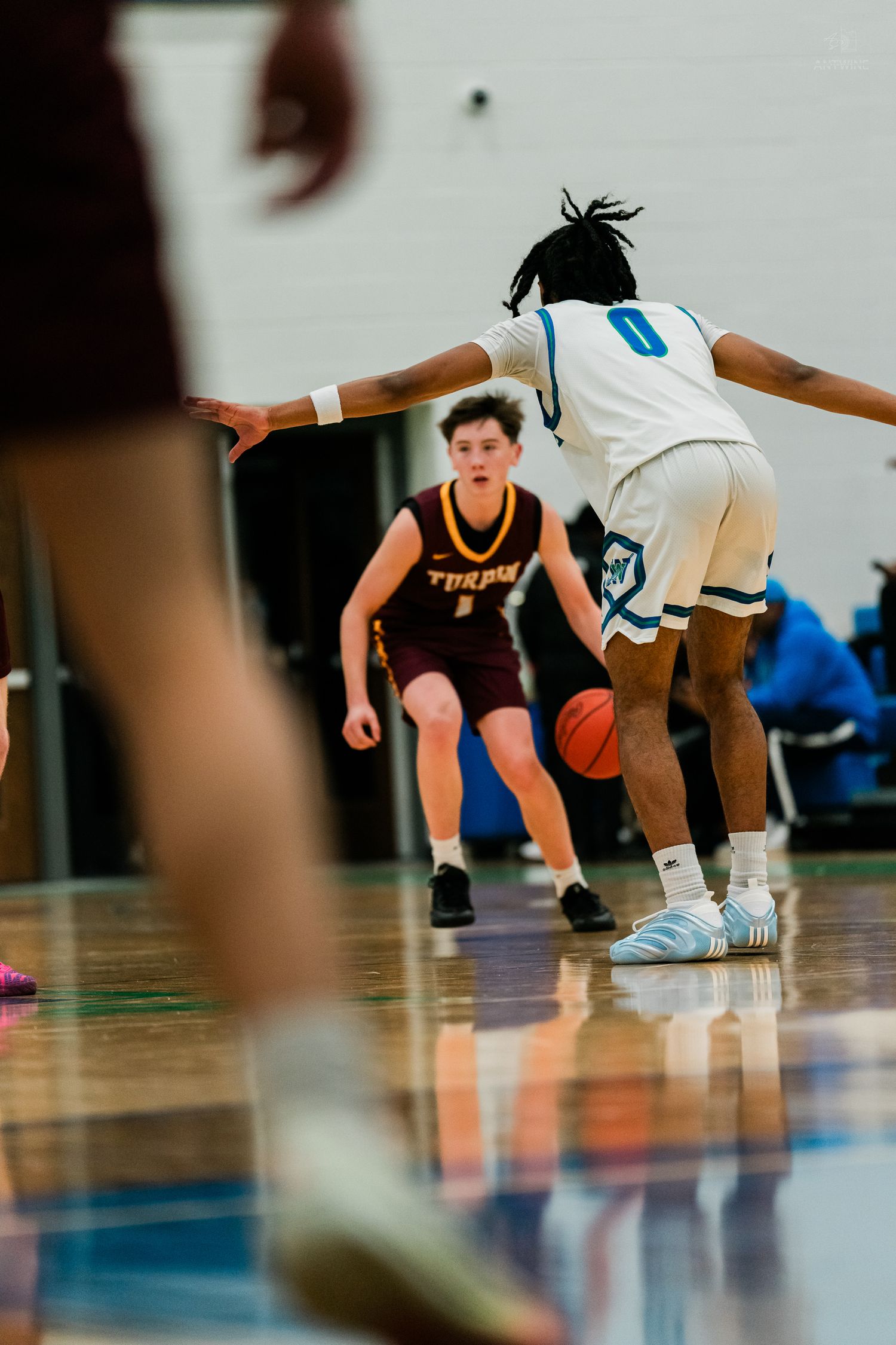 Player in maroon Turpin jersey dribbles basketball while defender in white number 0 jersey guards during high school game.
