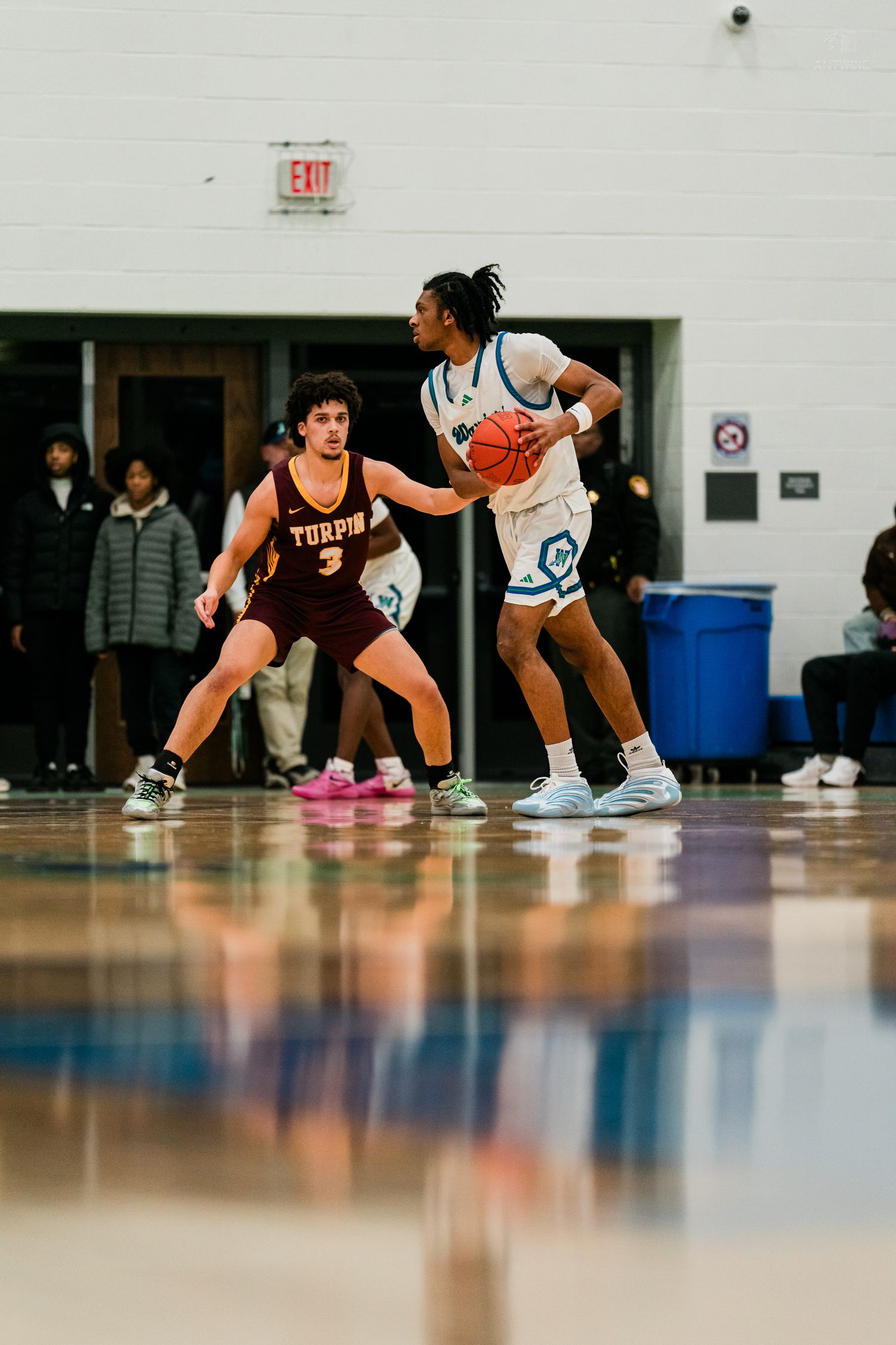 Basketball player in white uniform dribbles while defended by Turpin player #3 in maroon during indoor game.