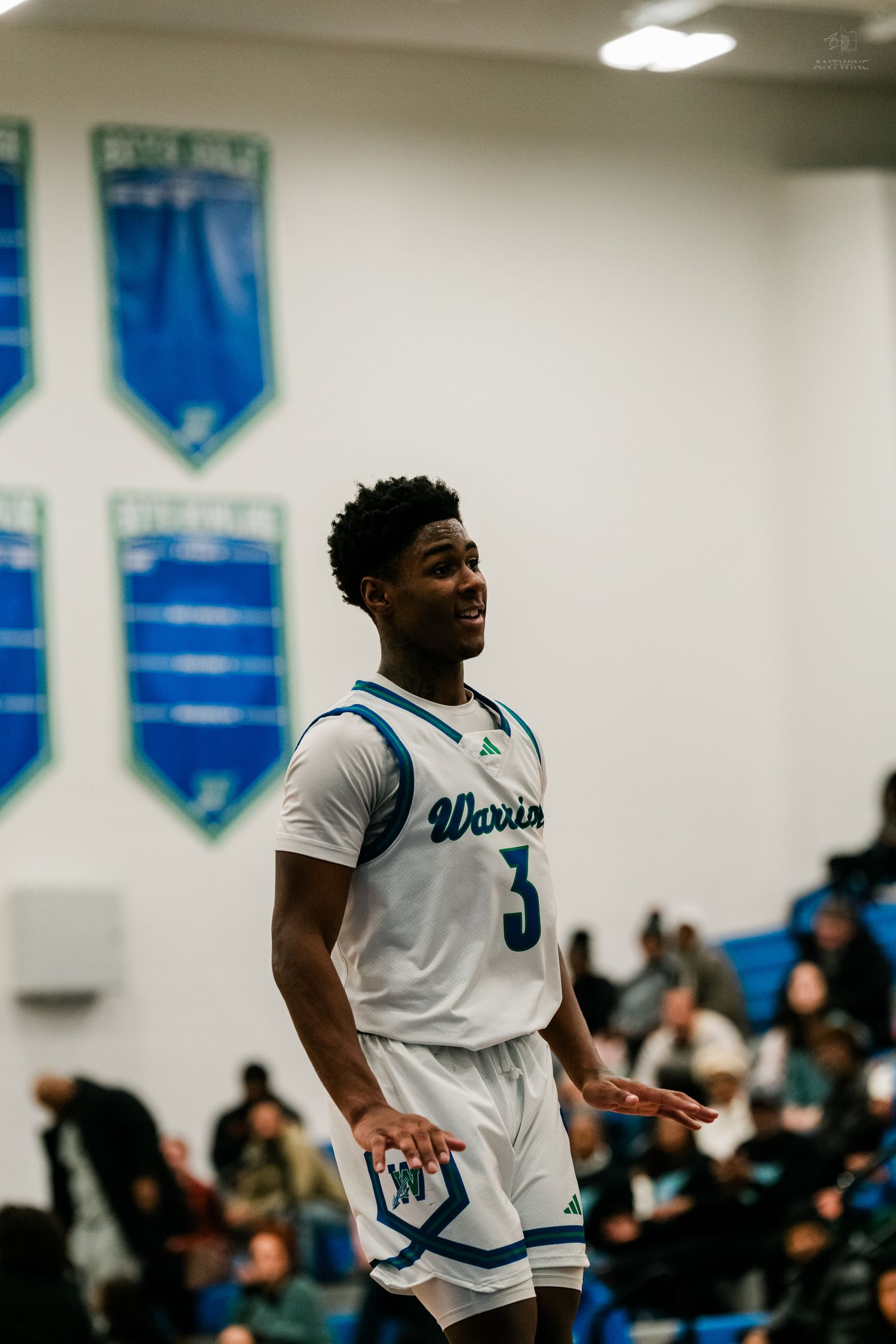 Winton Woods Warriors basketball player #3 reacts during a home game in a blue and white gymnasium.