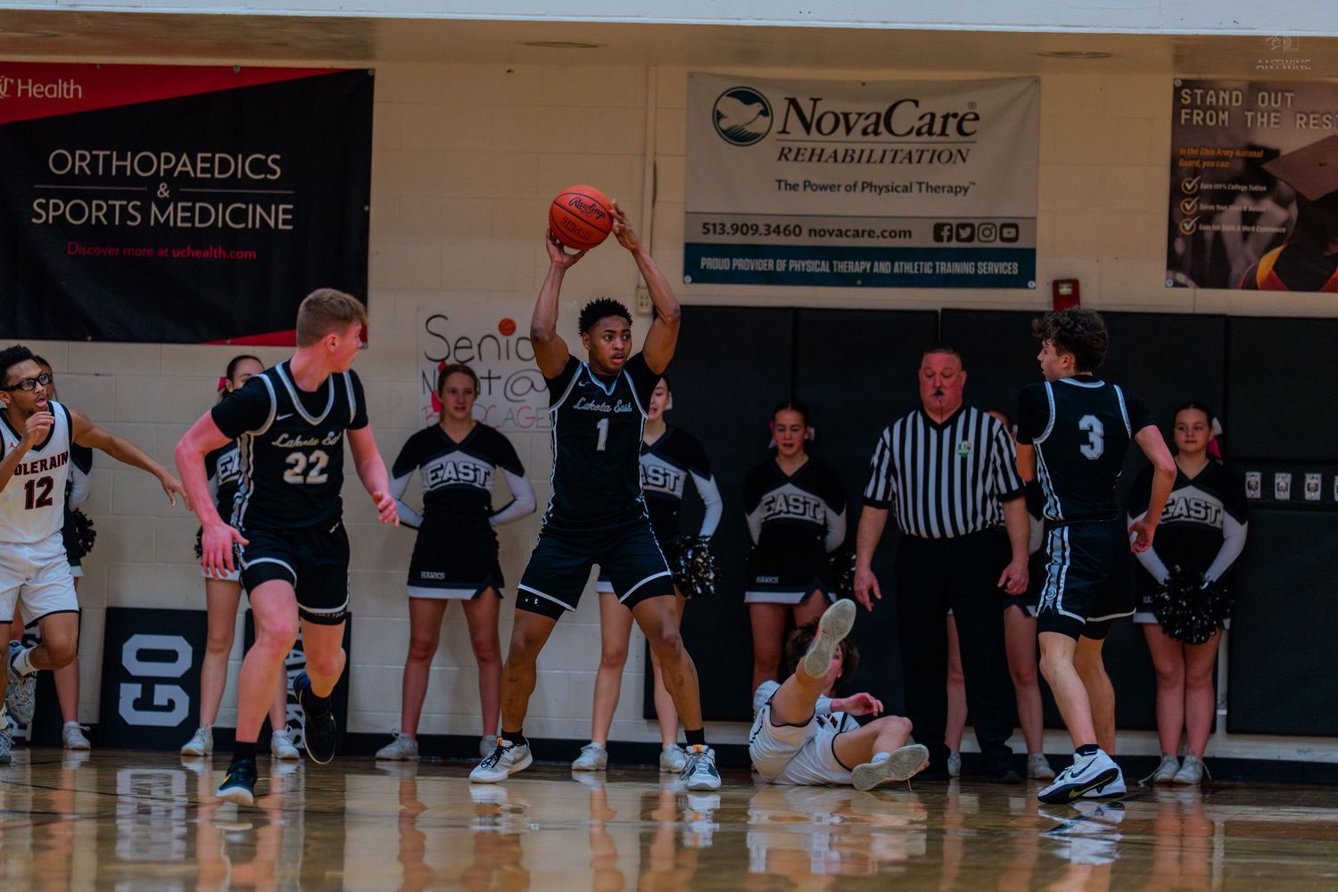 Basketball players in blue uniforms celebrate near the baseline during a high school basketball game.