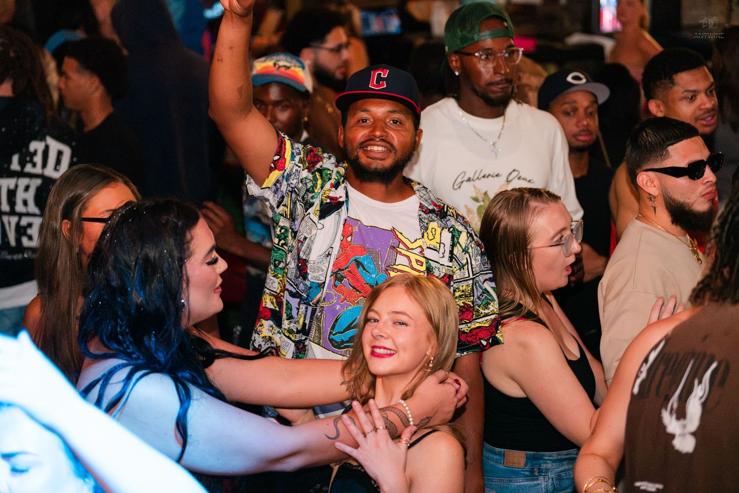 Diverse group of young adults dancing and socializing at a lively nightclub party.