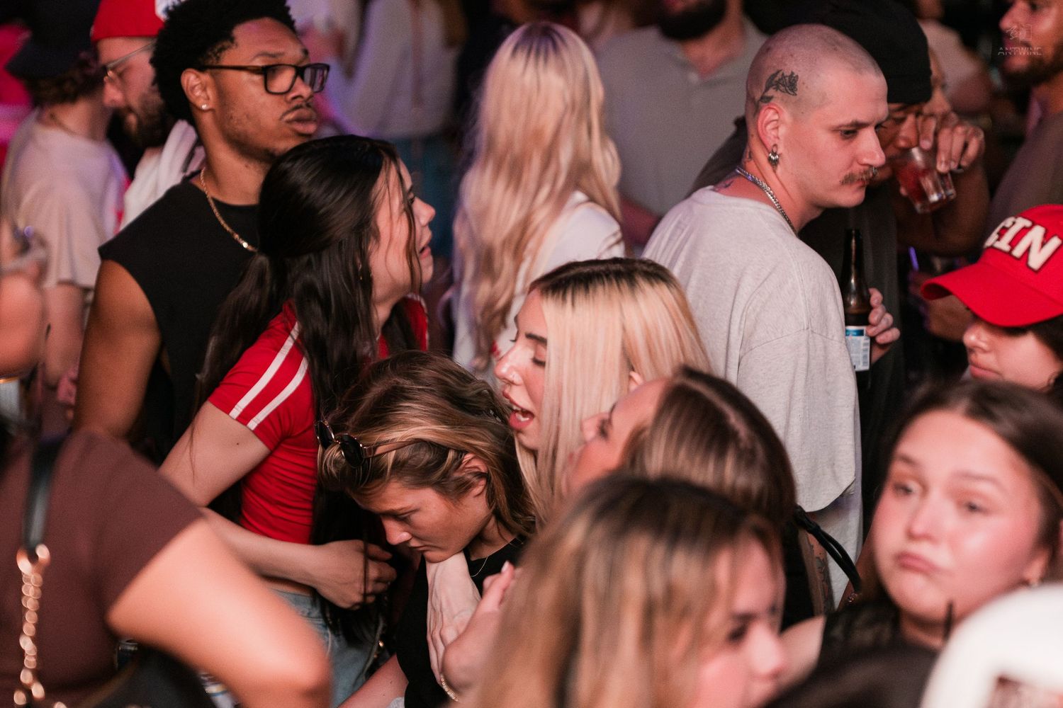 Young people mingling and dancing in a crowded nightclub atmosphere.