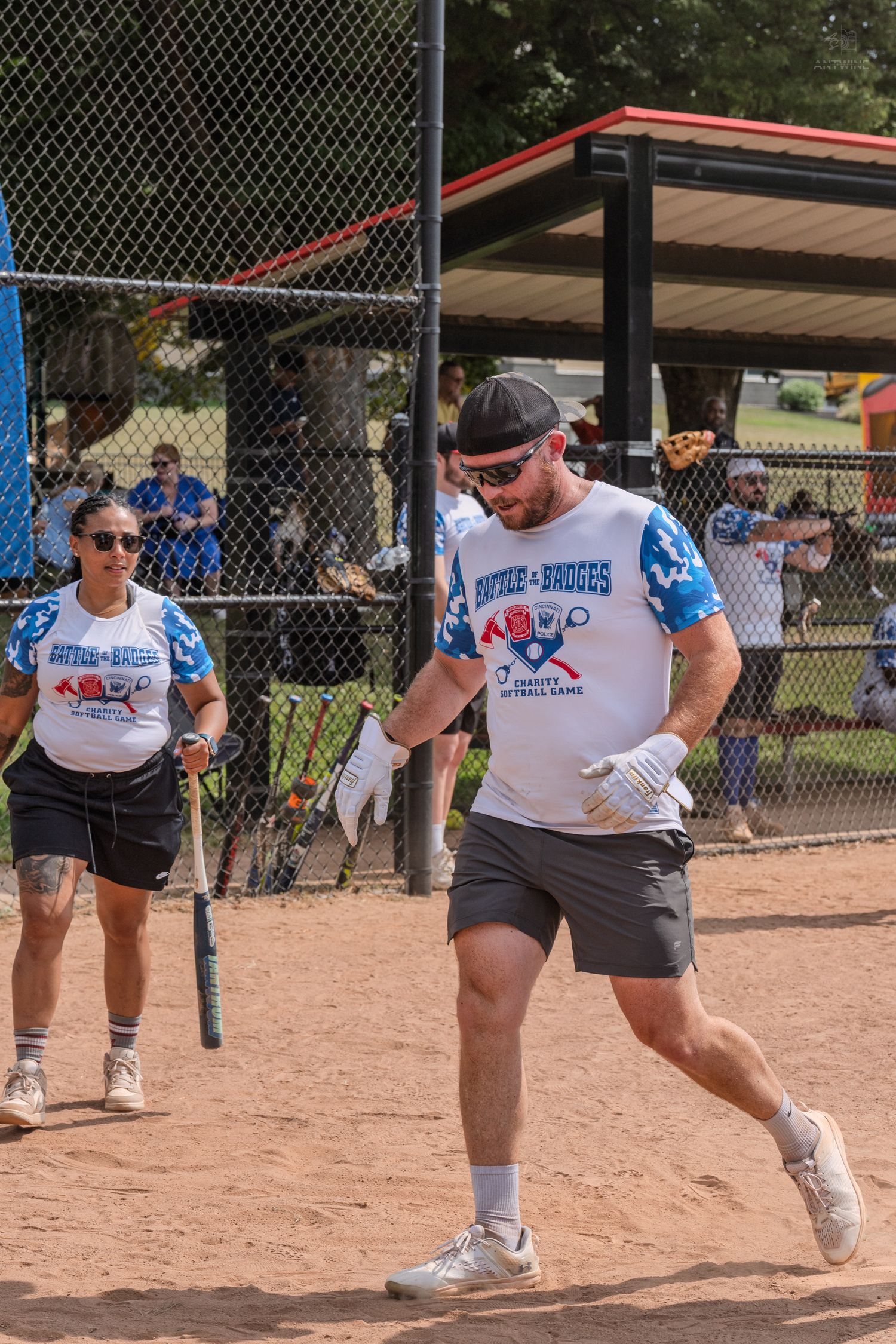 Man in softball uniform running bases during a recreational softball game on a sunny day.