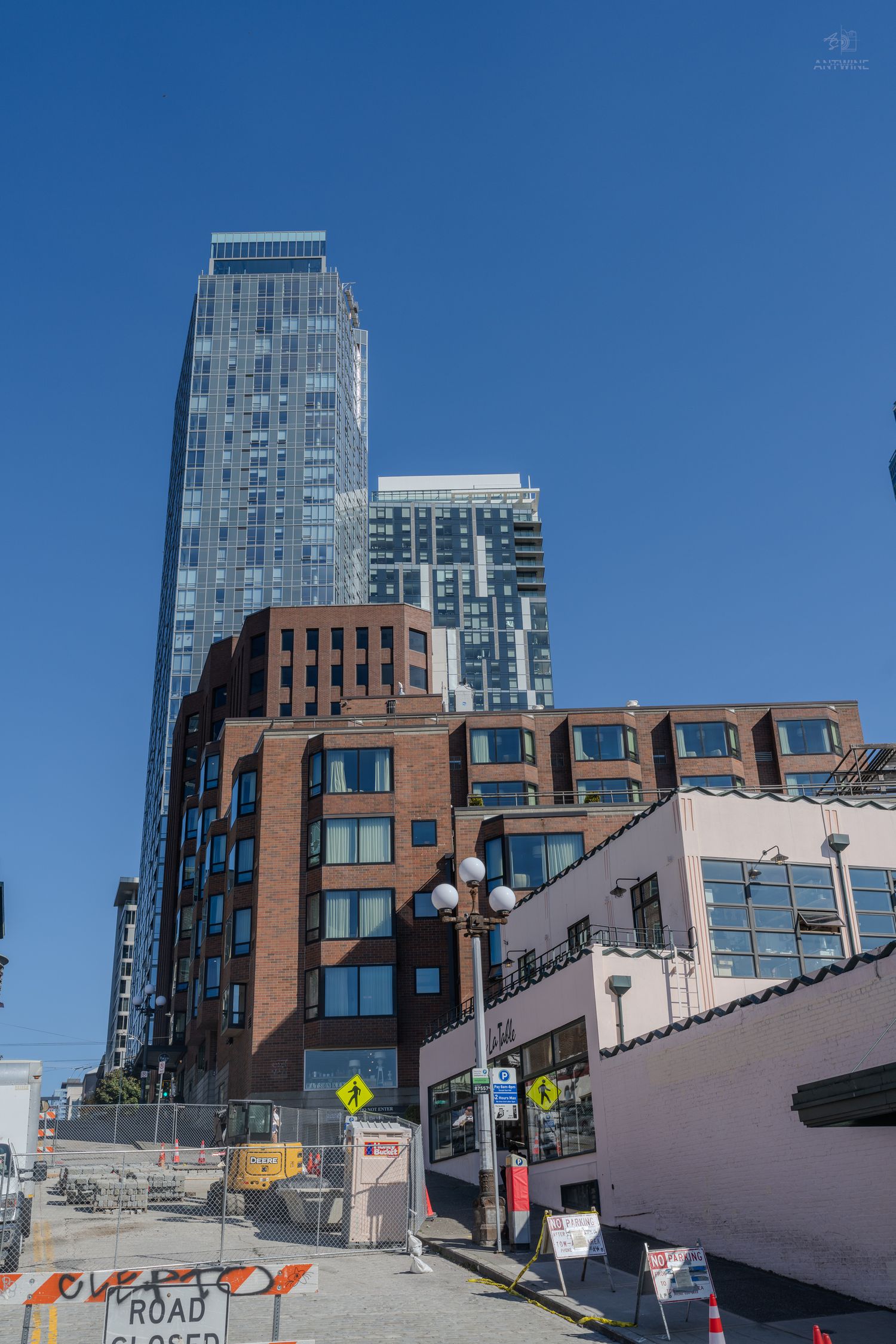 Urban cityscape with modern glass skyscraper rising above brick buildings with road closed signs.