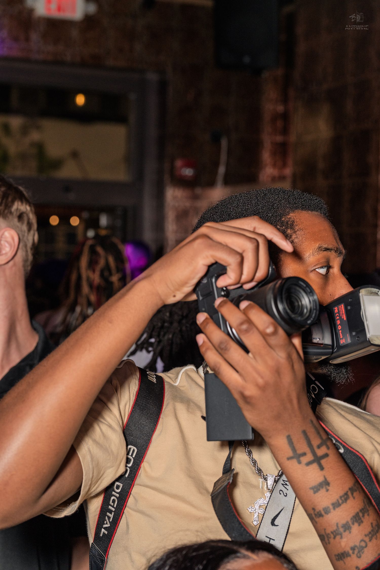 Photographer with Canon DSLR camera capturing moments at a lively nightclub event.